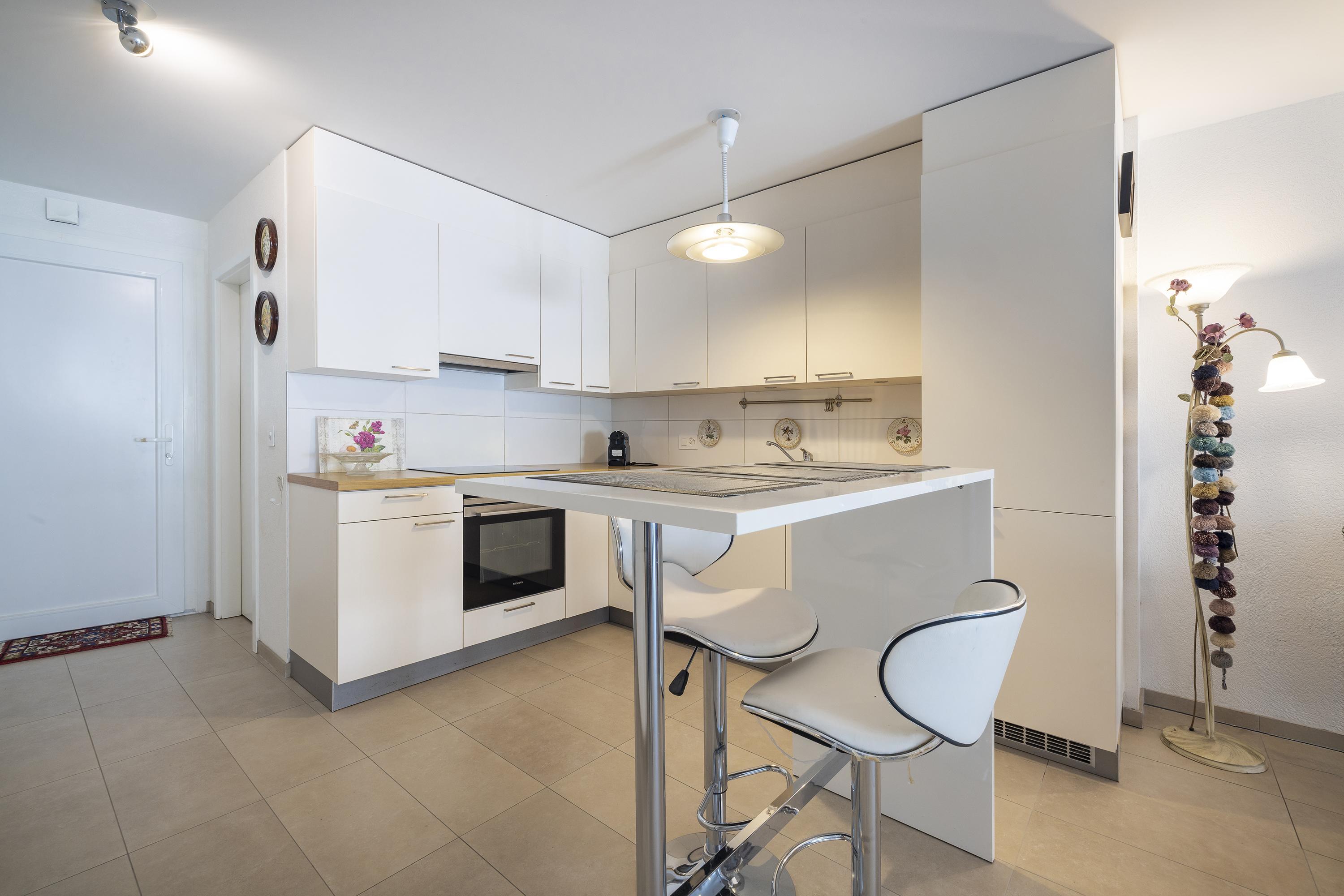 Moderne weiße Küche mit Insel und Barhockern