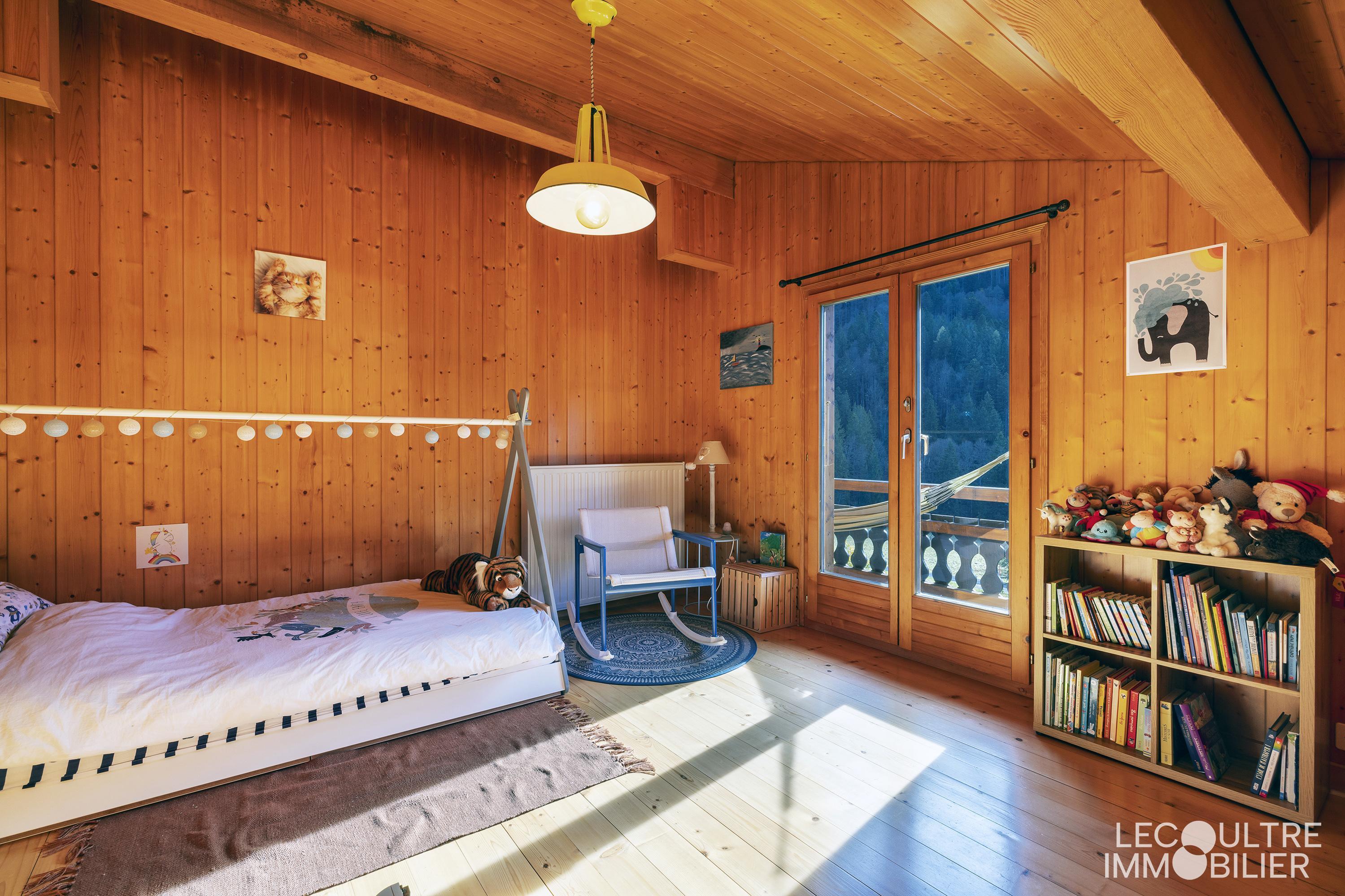 Holzverkleidetes Schlafzimmer mit Balkonzugang