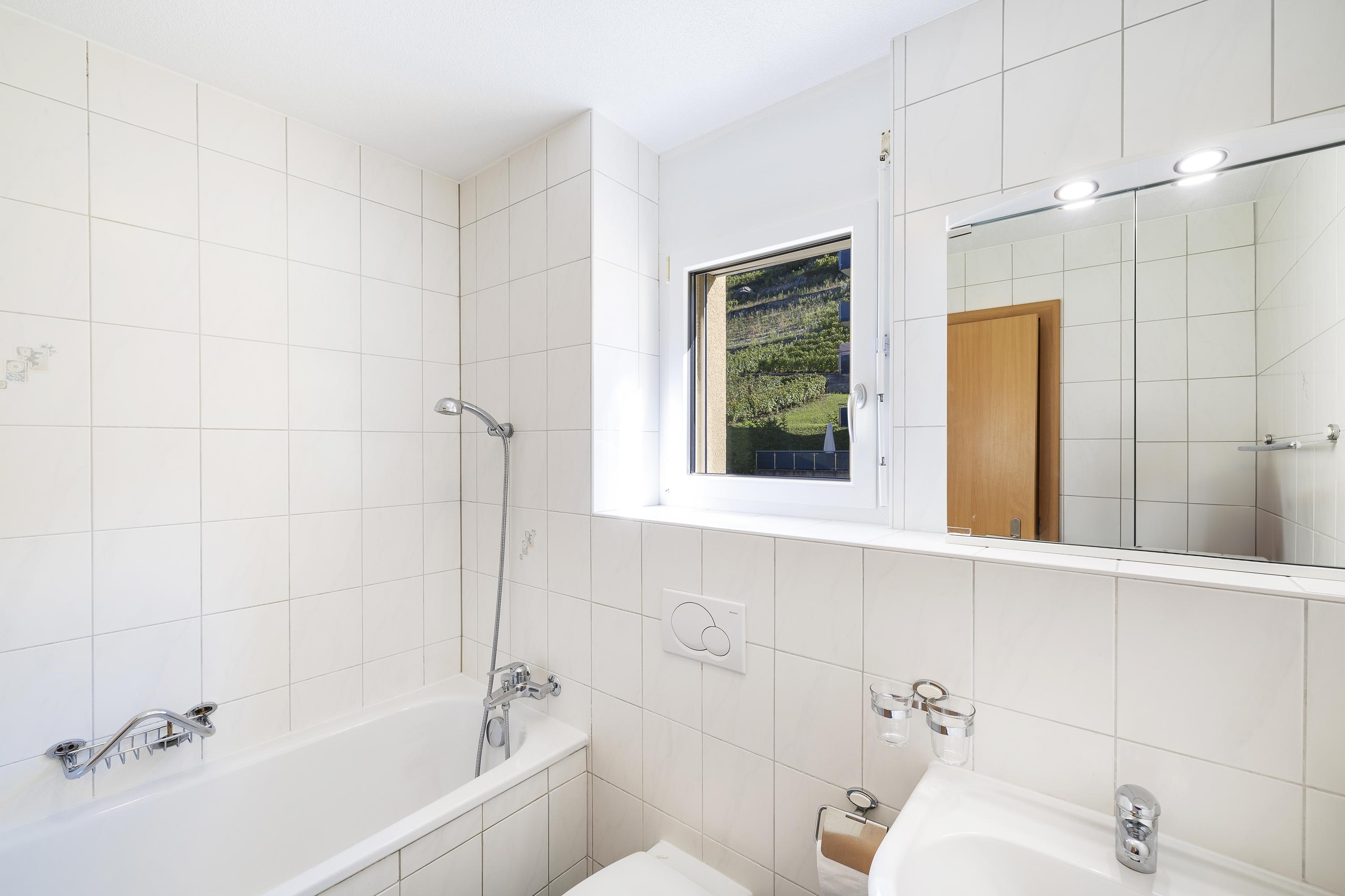 Helles Badezimmer mit Badewanne und Fenster