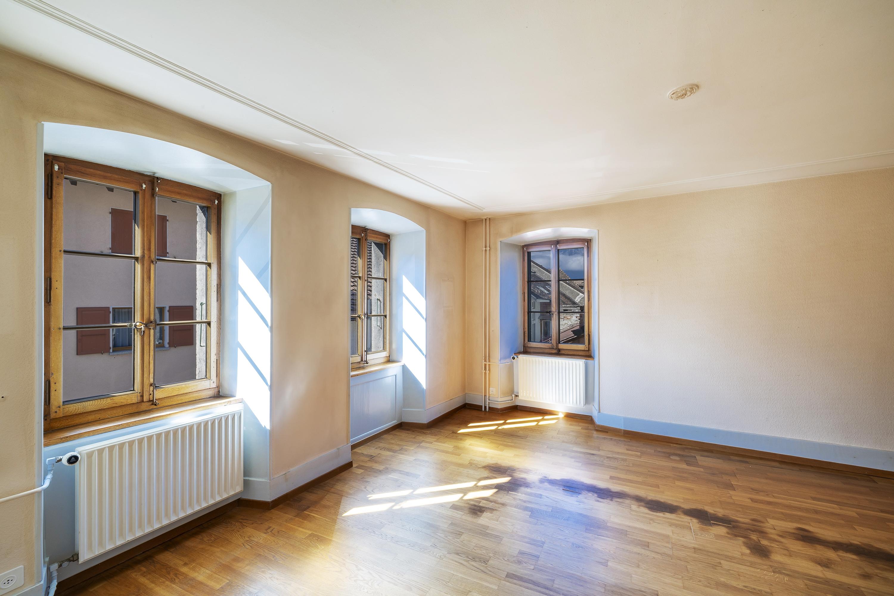 Leerer heller Wohnraum mit Fenstern und Holzparkett