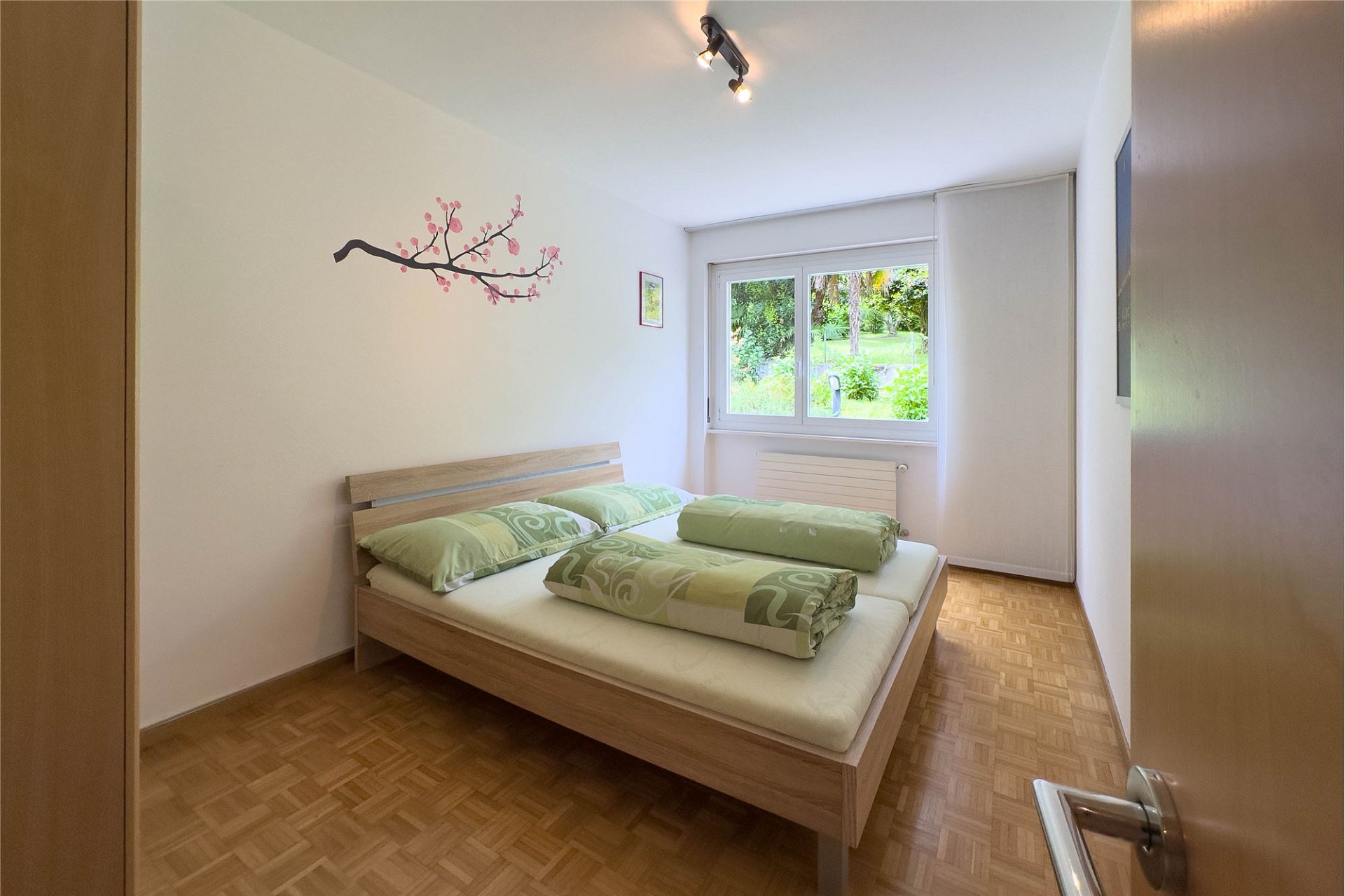 Helles Schlafzimmer mit Doppelbett und Gartenblick