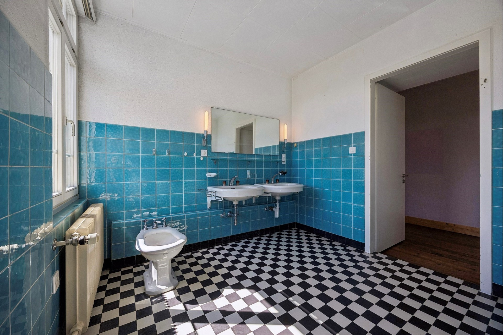 Badezimmer mit blau gefliesten Wänden und Schachbrettboden