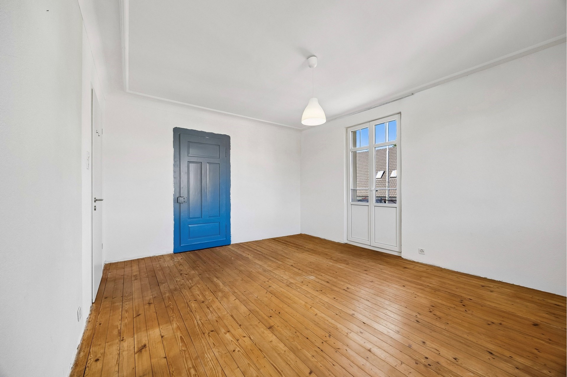 Leerer, heller Raum mit Holzdielen und blauem Innentor