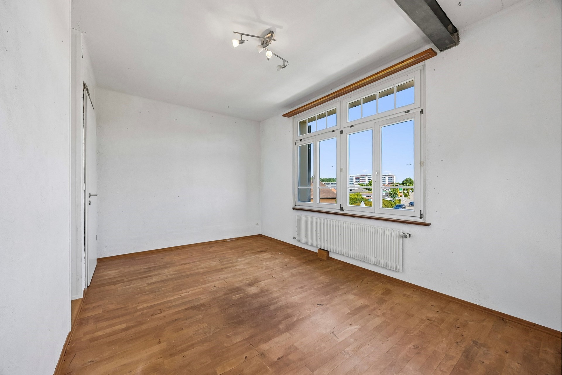 Heller leerer Raum mit Holzboden und großem Fenster
