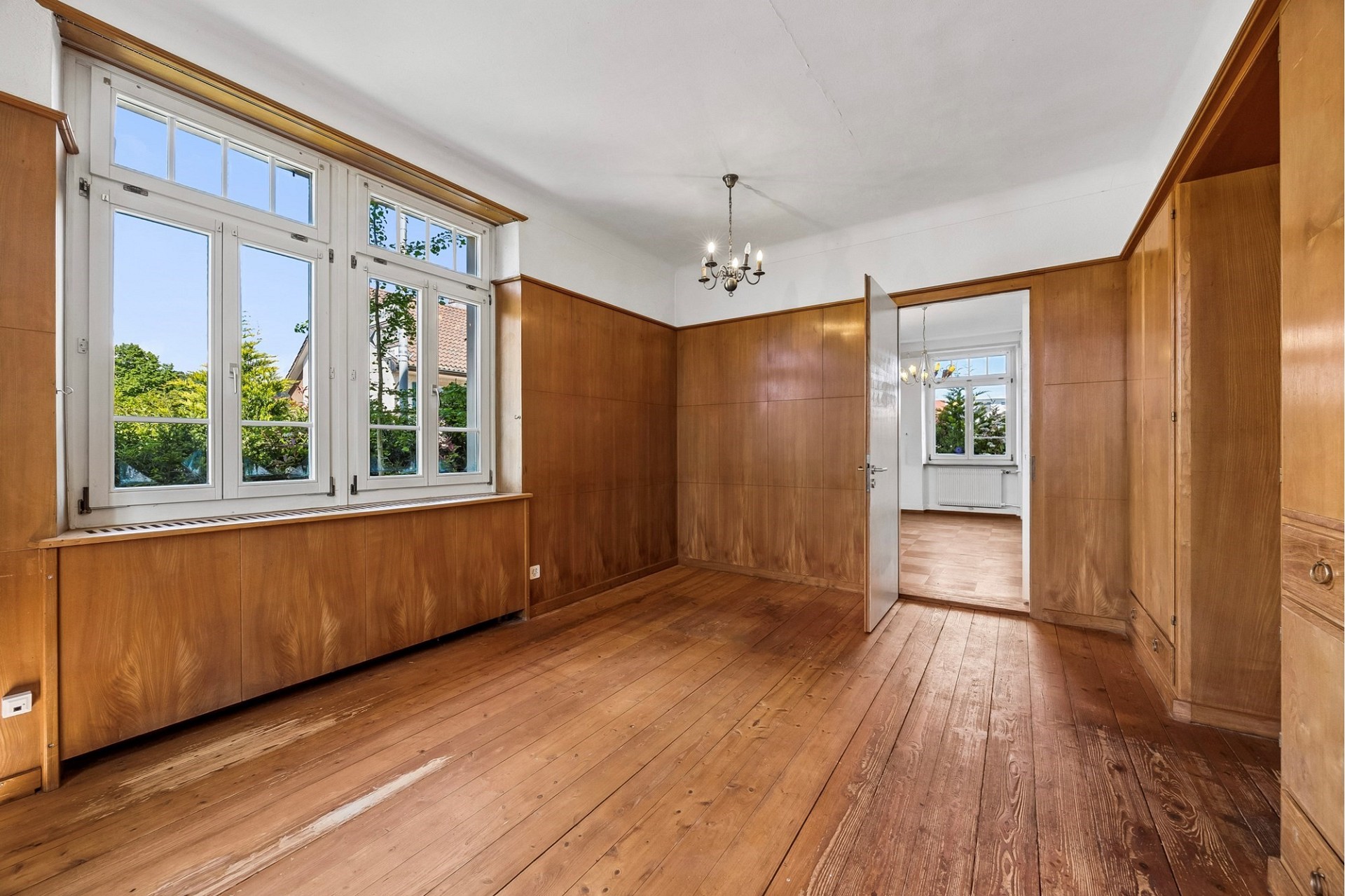 Wohnzimmer mit Holzvertäfelung und großen Fenstern