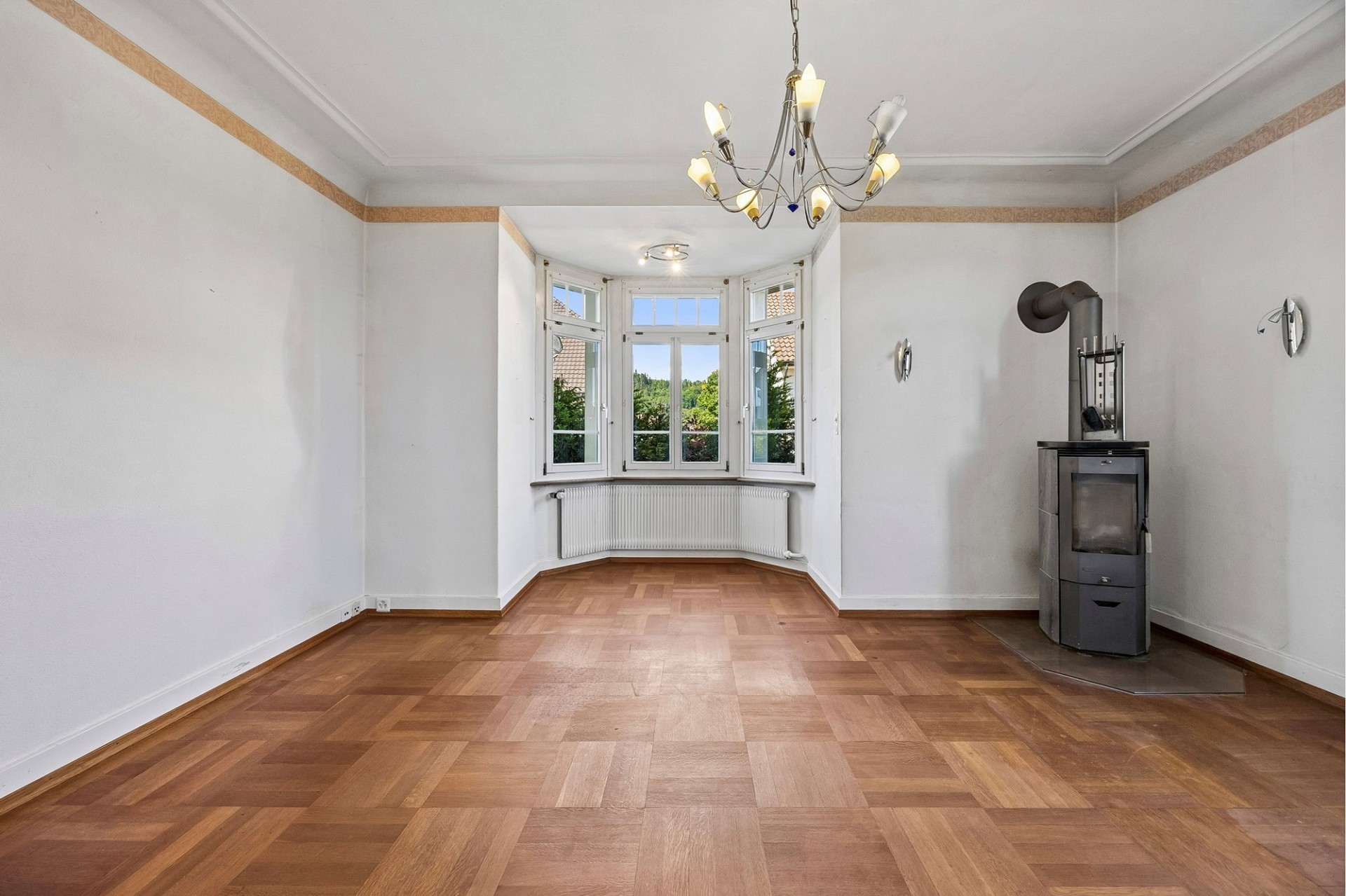Heller leerer Wohnraum mit Kaminofen und Erkerfenster