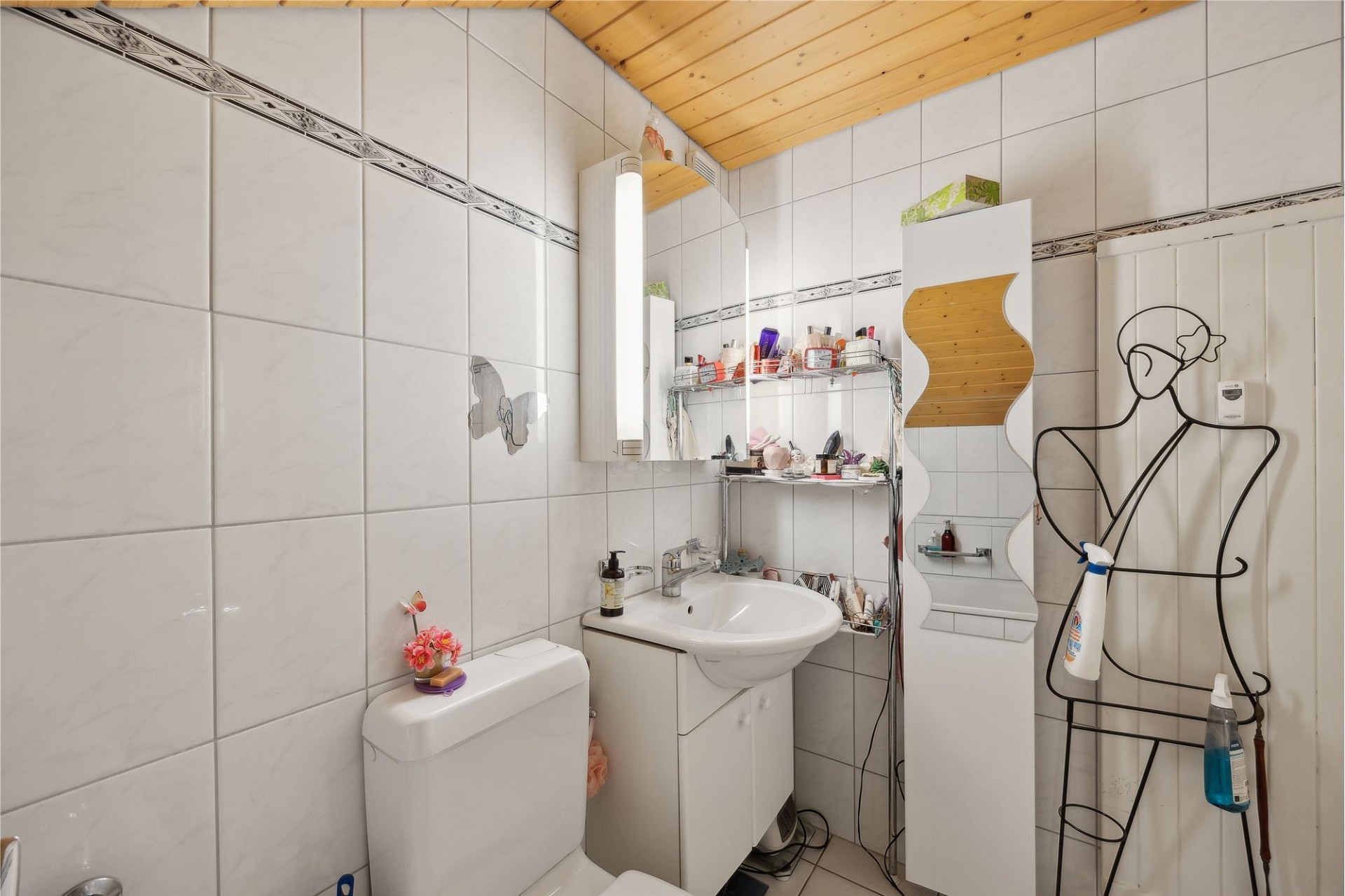 Kleines, helles Badezimmer mit weiß gefliesten Wänden und Holzdecke