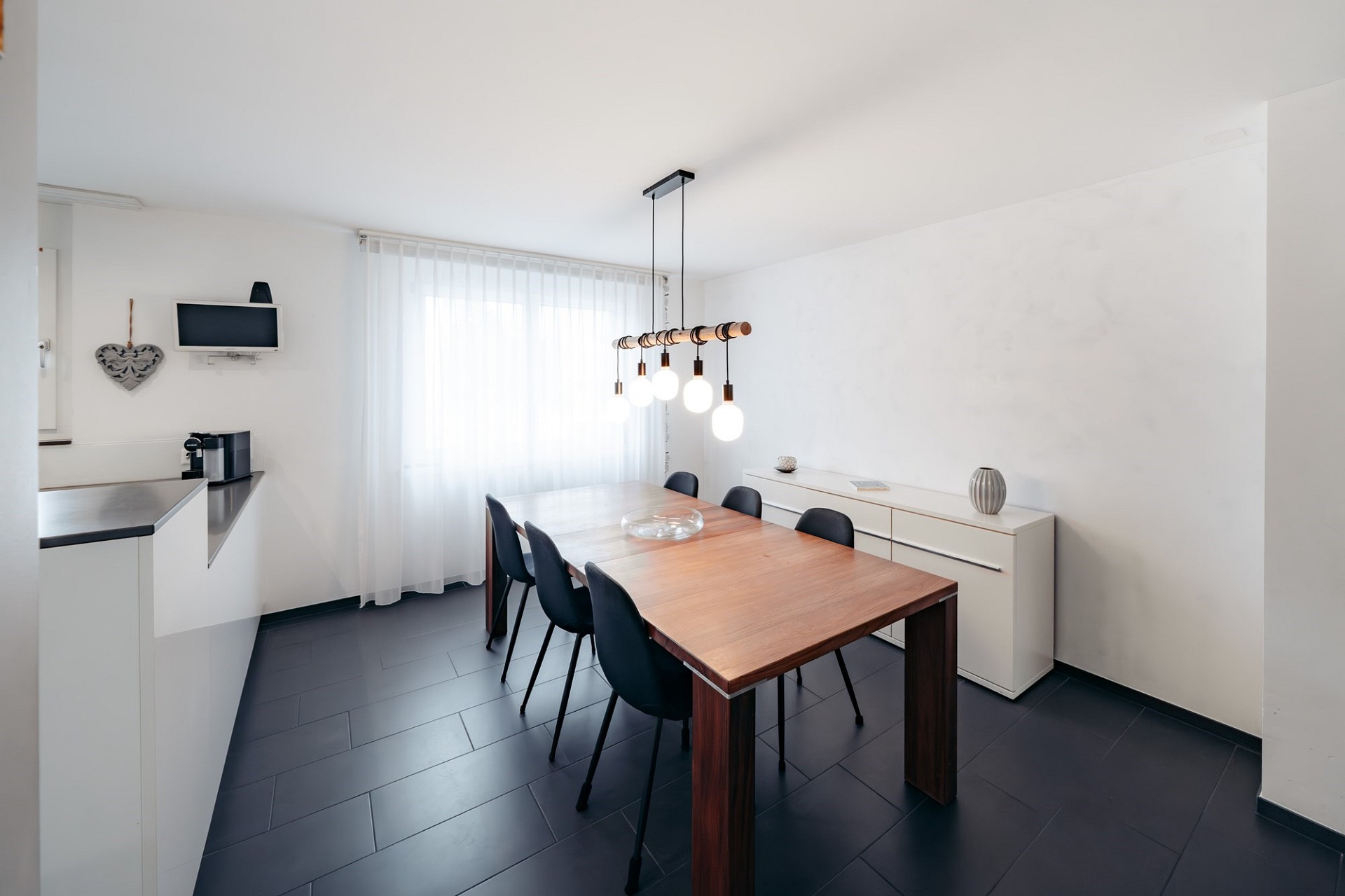 Modernes Esszimmer mit schwarzem Boden und Holztafel