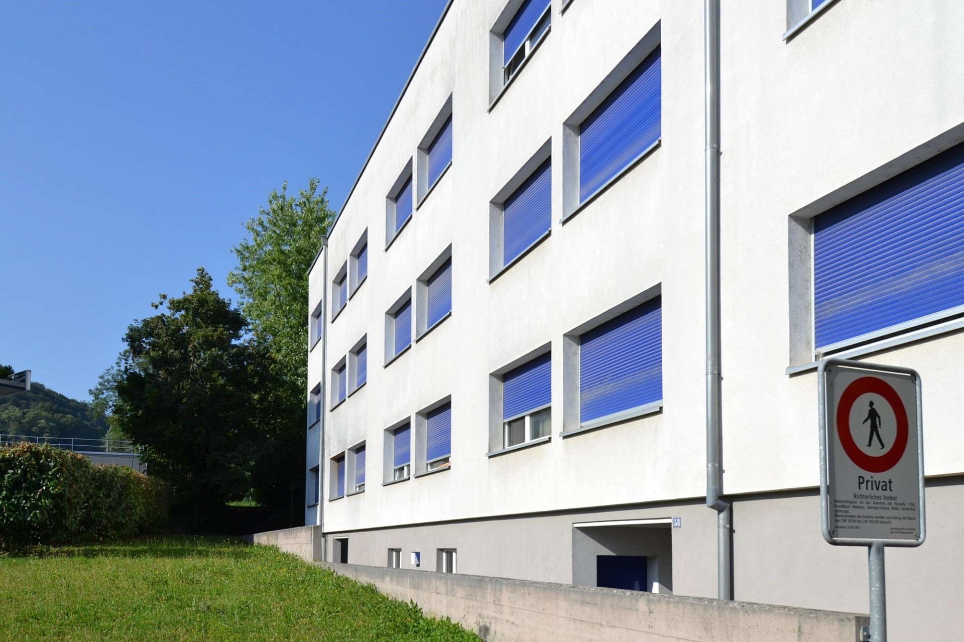 Modernes Mehrfamilienhaus mit weißer Fassade und blauen Fensterläden