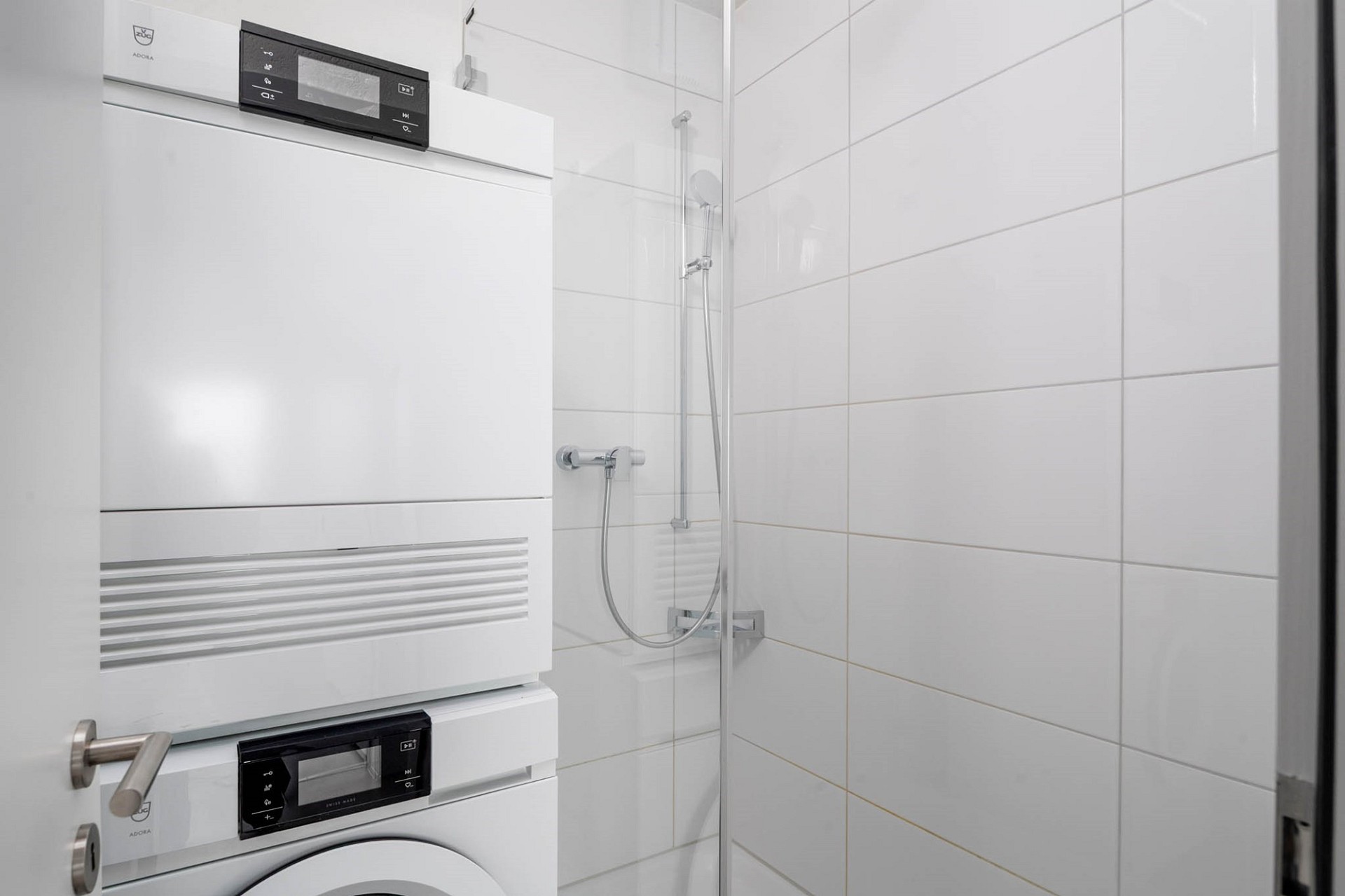 Badezimmer mit Dusche und gestapelter Waschtrockner-Säule