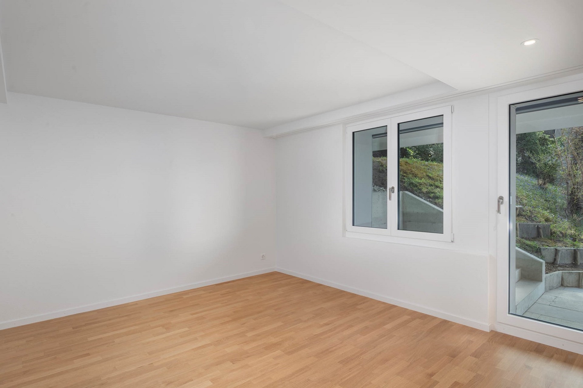 Heller leerer Raum mit Holzoptikboden und großen Fenstern