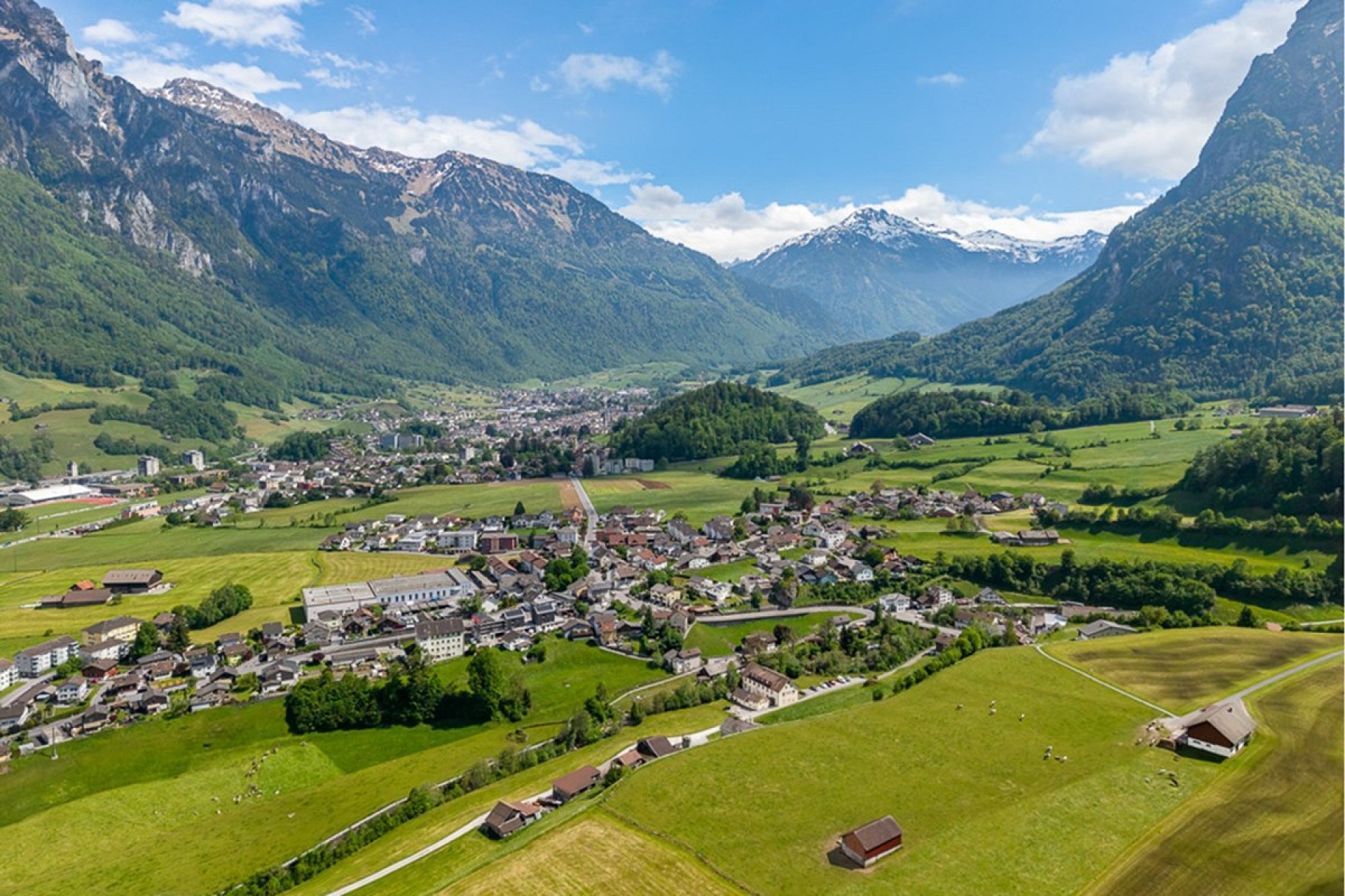 Luftaufnahme eines alpinen Tals mit Ortschaft