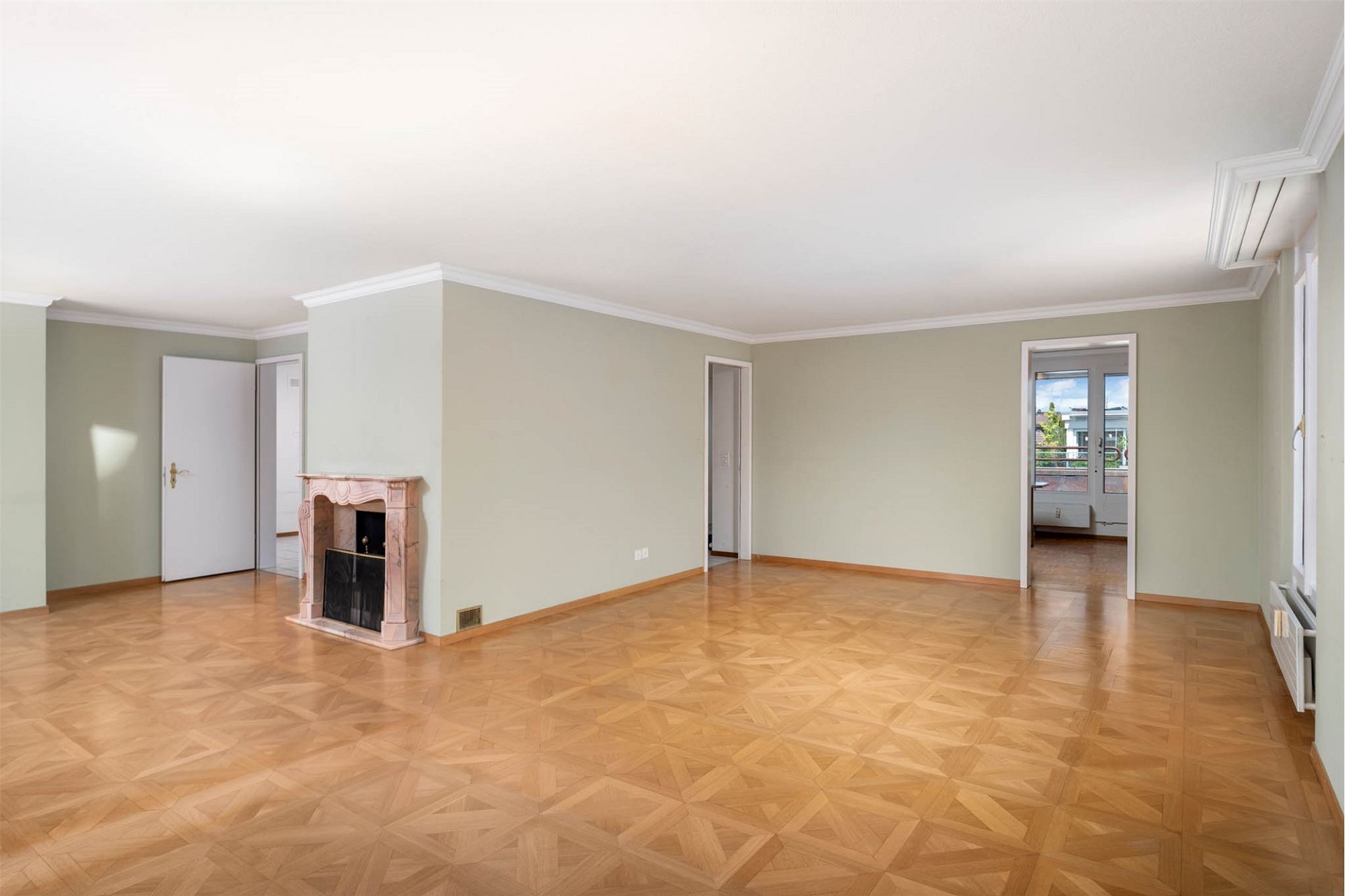 Großer leerer Wohnraum mit Kamin und Parkett
