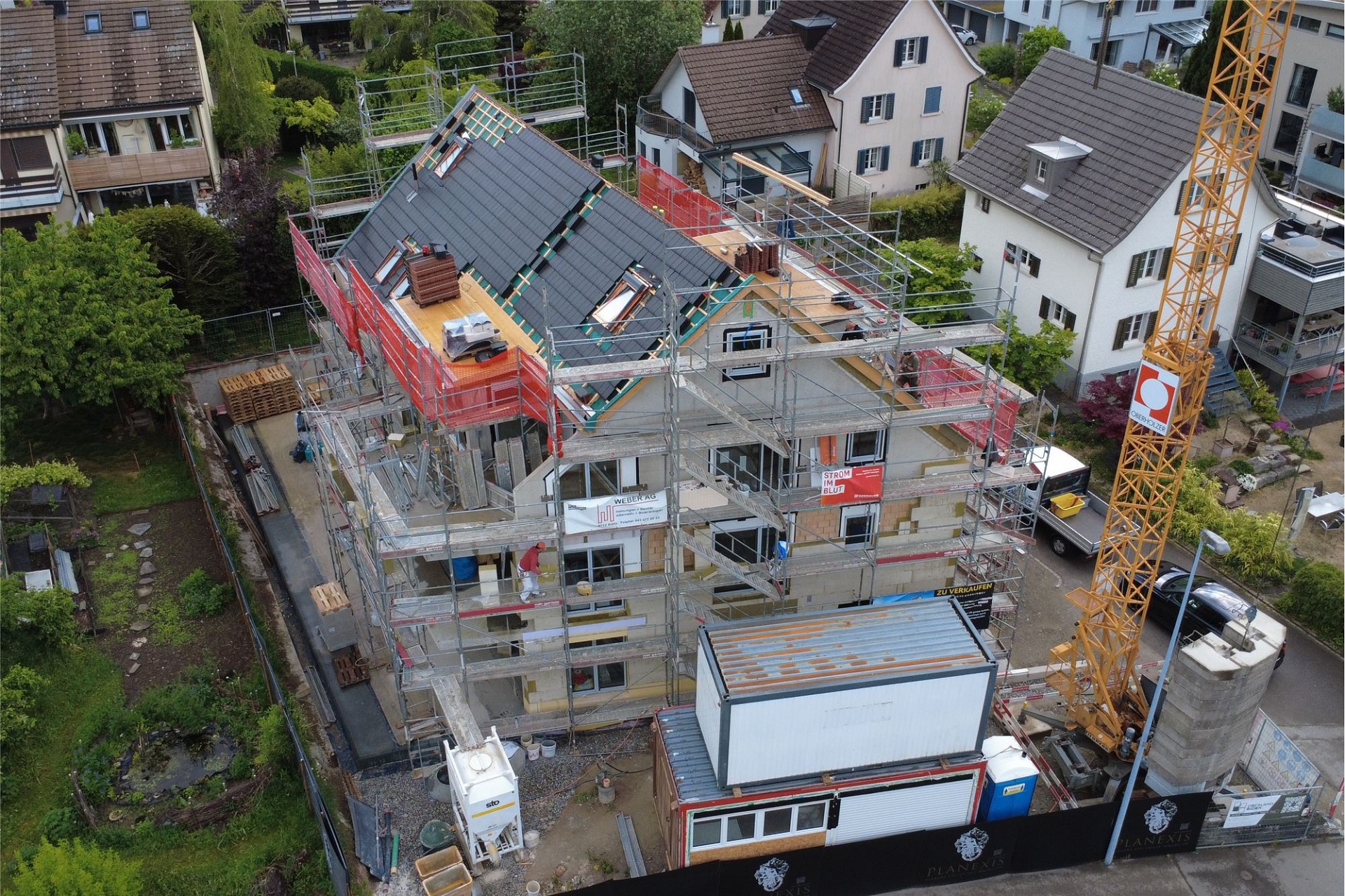 Luftaufnahme einer Baustelle mit eingerüstetem Mehrfamilienhaus