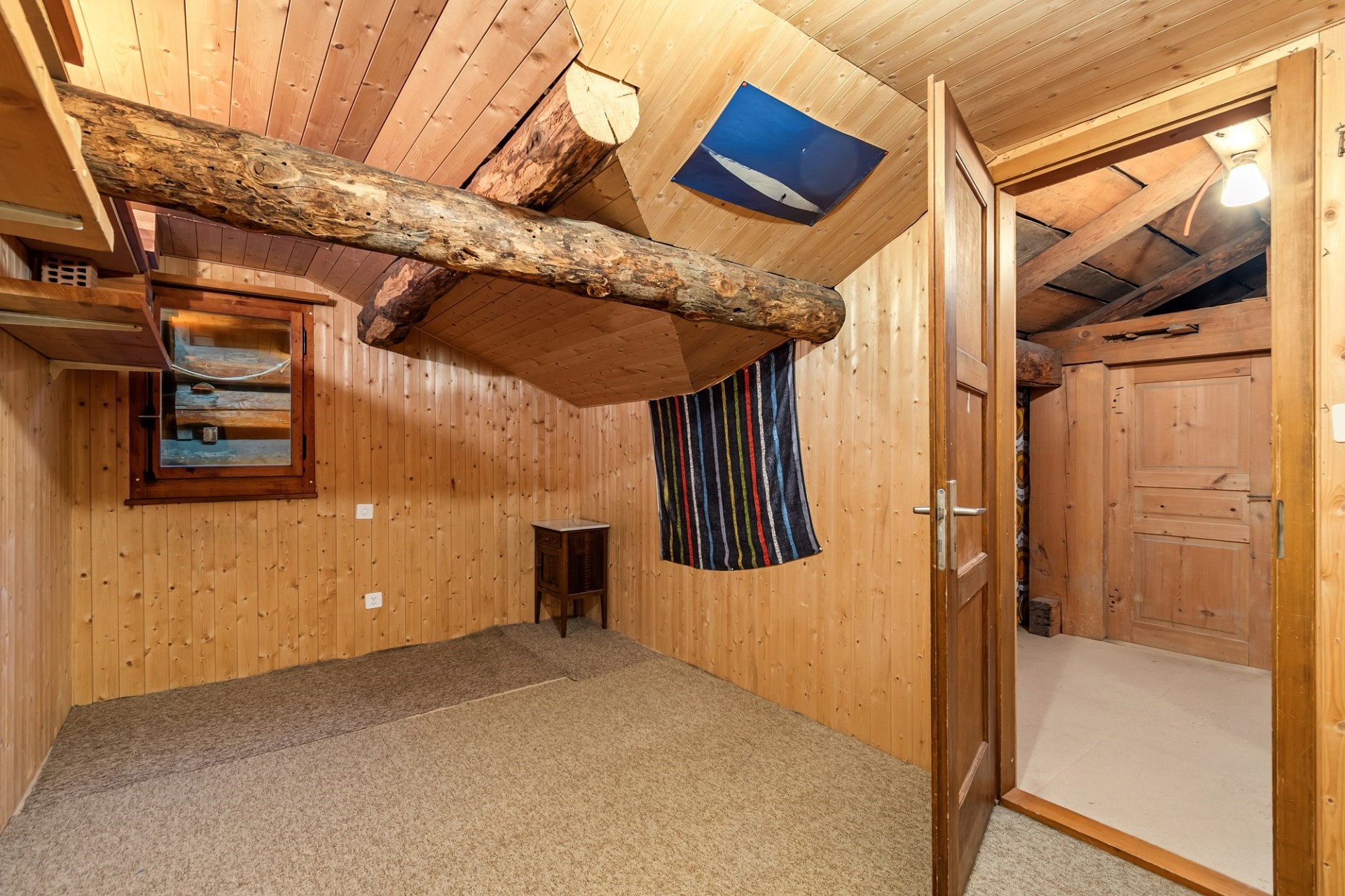 Holzverkleidetes Dachgeschosszimmer mit rustikalen Balken