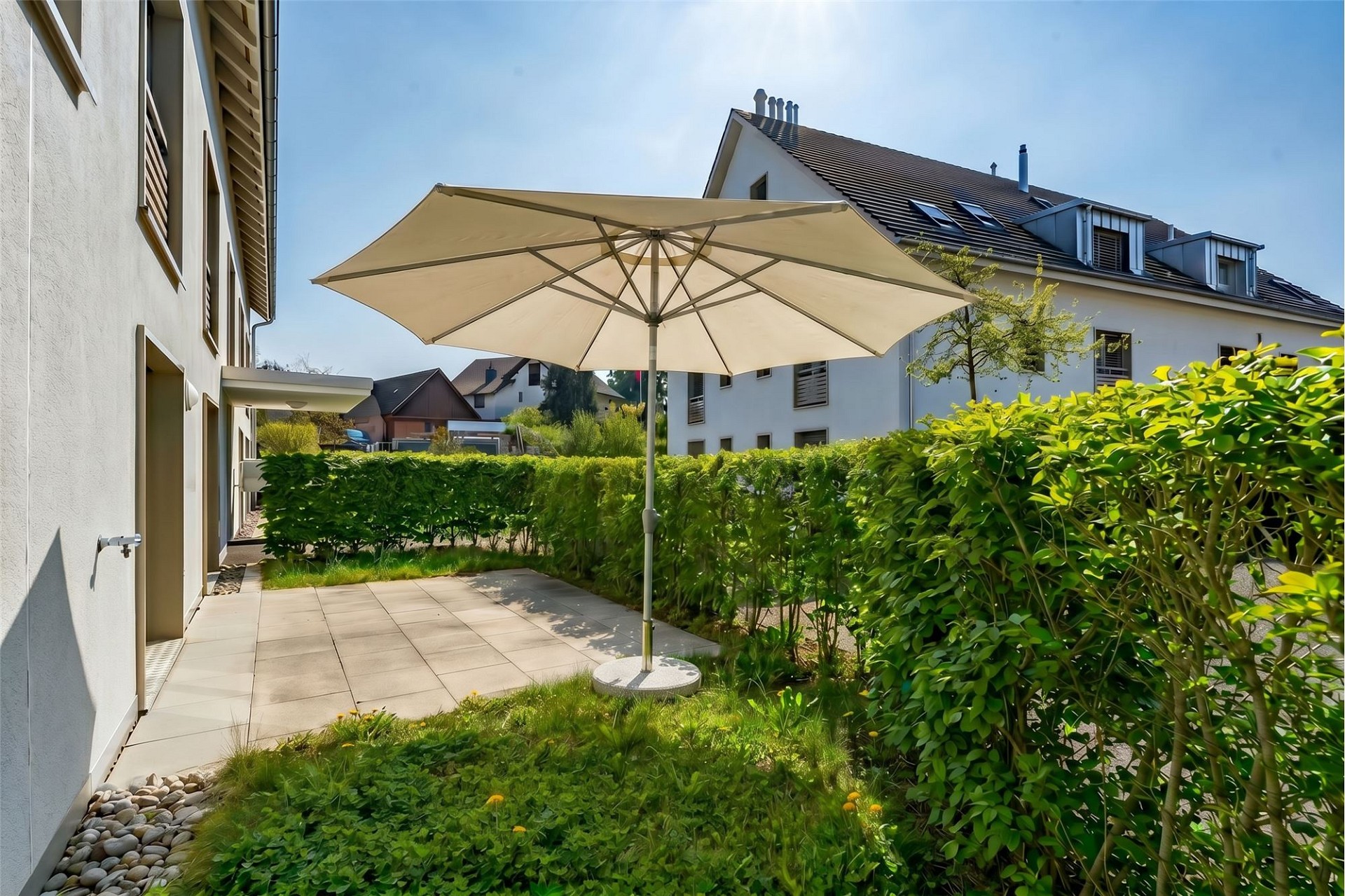 Gepflegter Gartenbereich mit Terrasse und Sonnenschirm