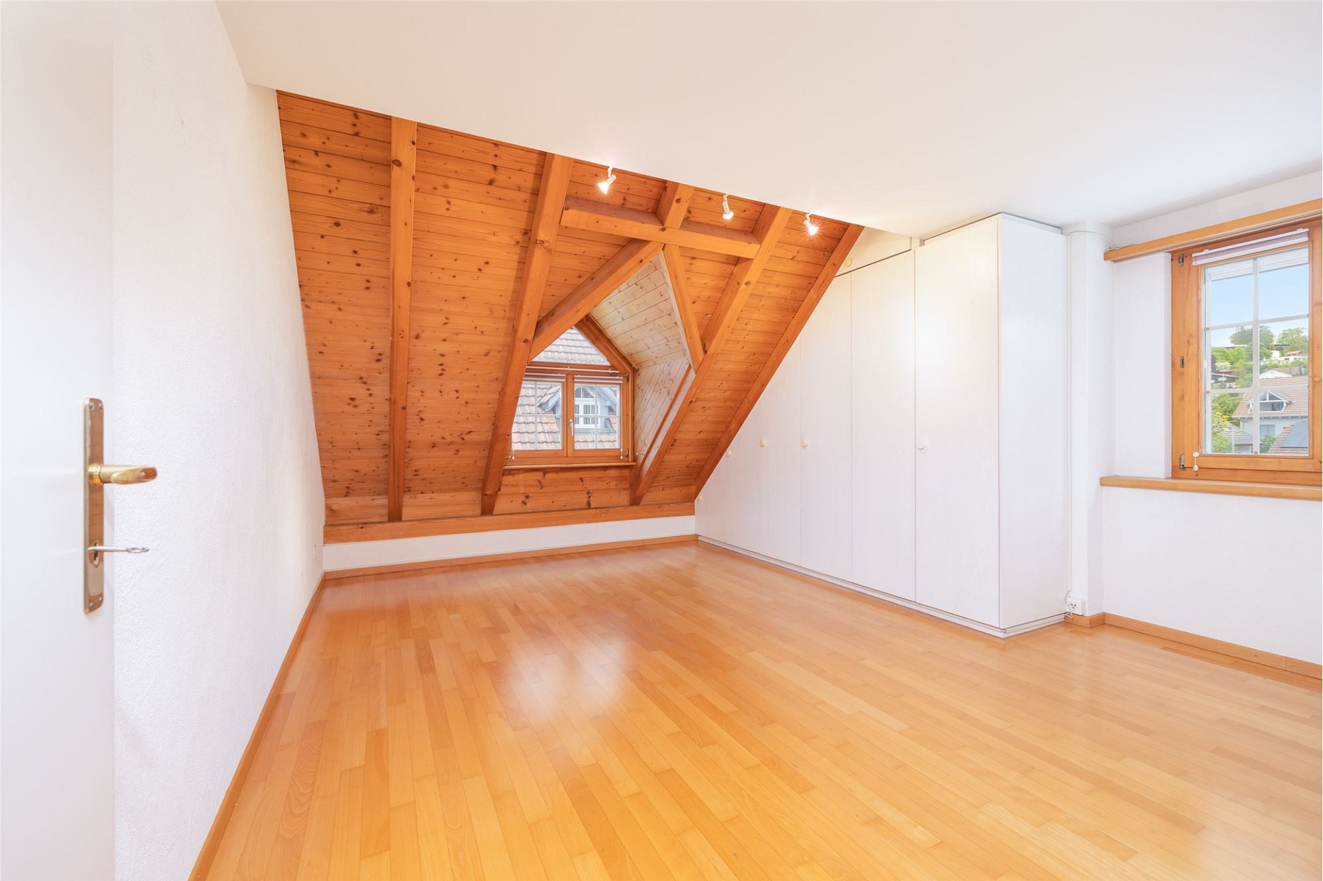 Heller Dachgeschossraum mit Holzbalken und Einbauschränken