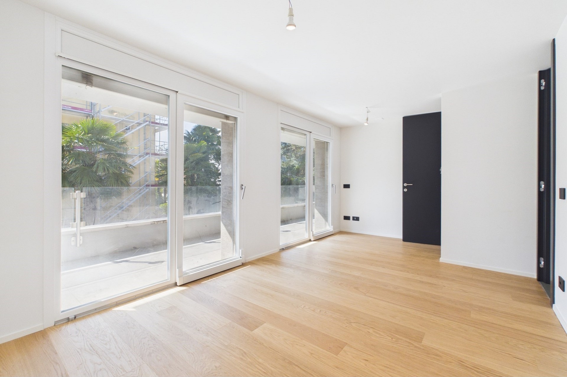 Helles, leeres Zimmer mit großen Schiebetüren zur Terrasse/Balkon