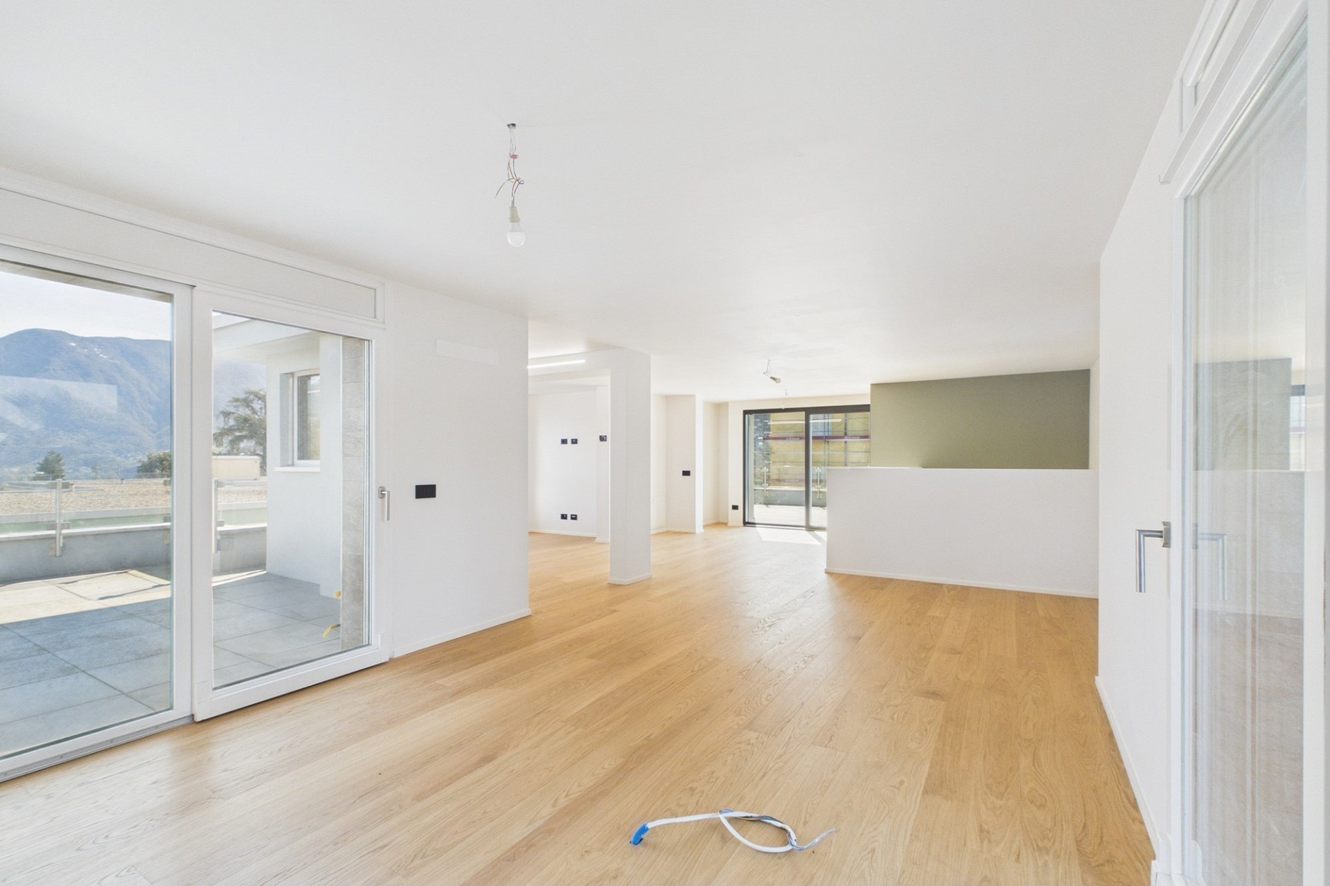 Heller, leerer Wohnraum mit Terrasse und Bergblick