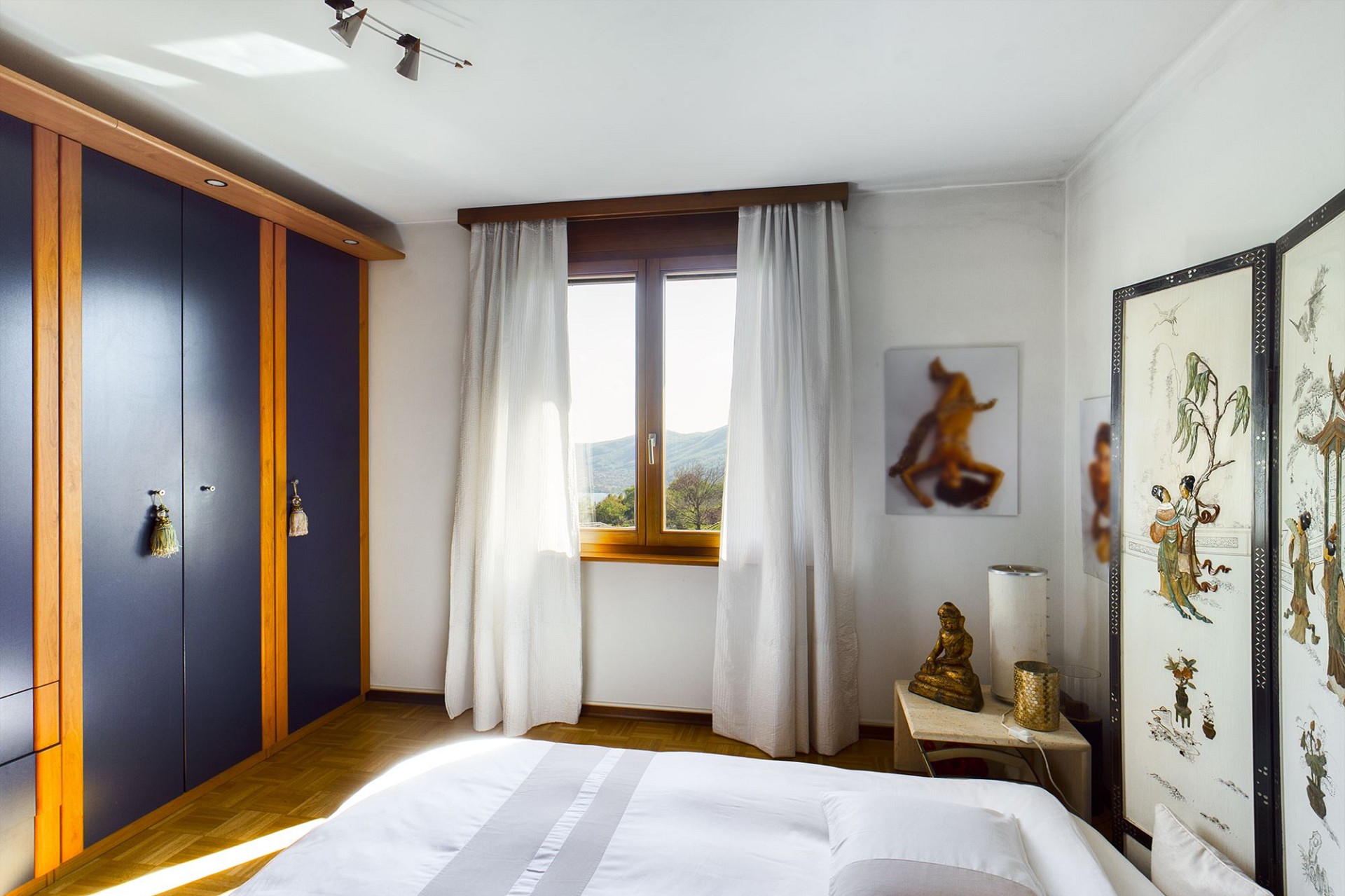 Helles Schlafzimmer mit Einbauschrank und Fensterblick