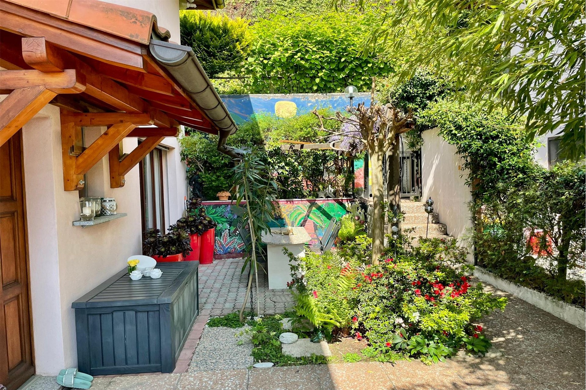 Üppiger Garten- und Terrassenbereich mit Holzvordach