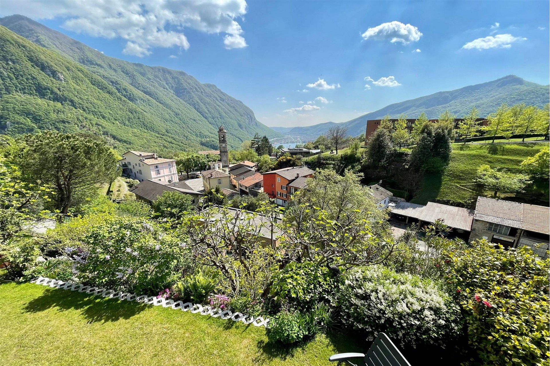 Berg- und Seeblick über ein grünes Dorf