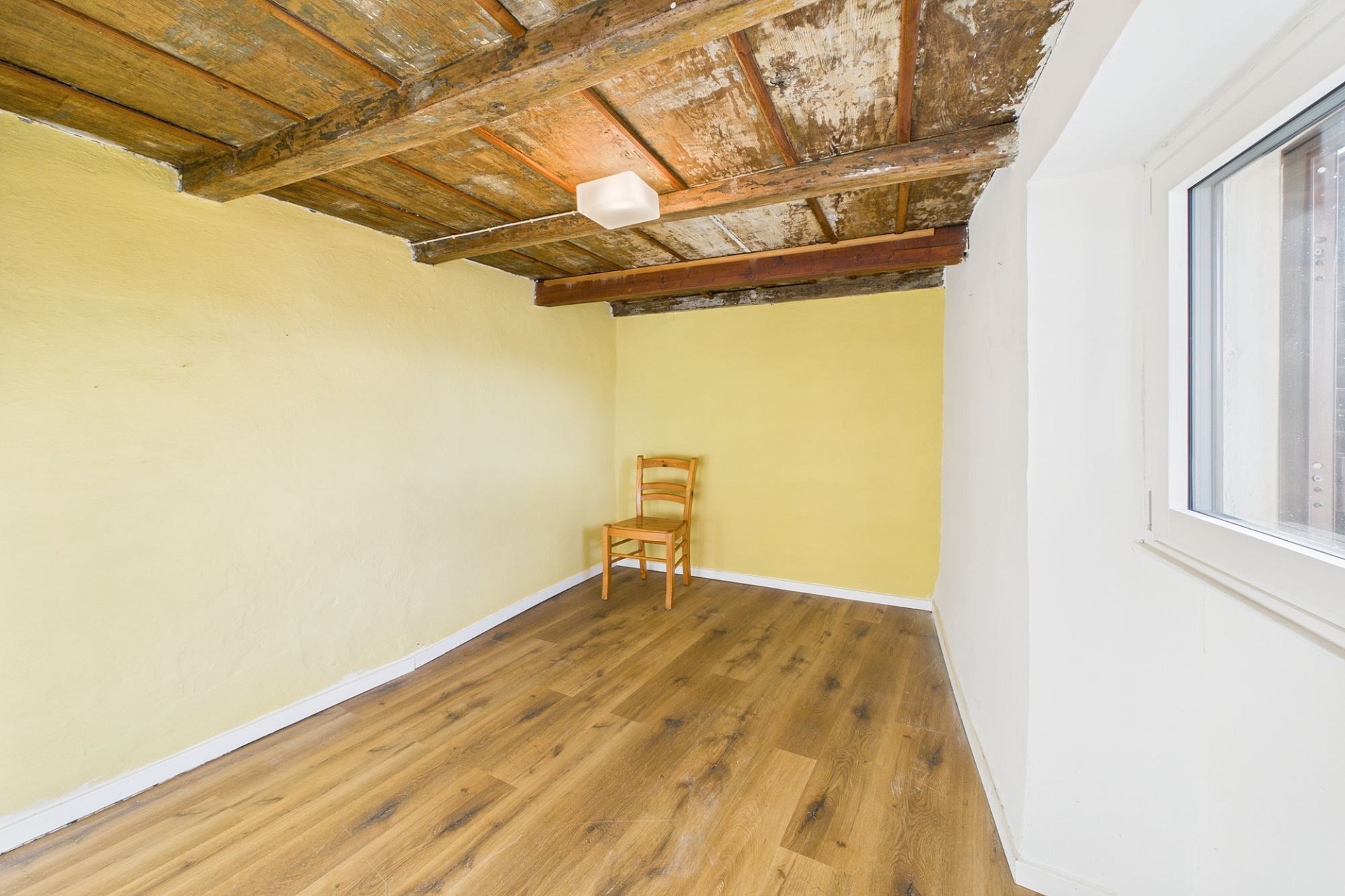 Kleiner Raum mit sichtbaren Holzbalken und Holzfußboden