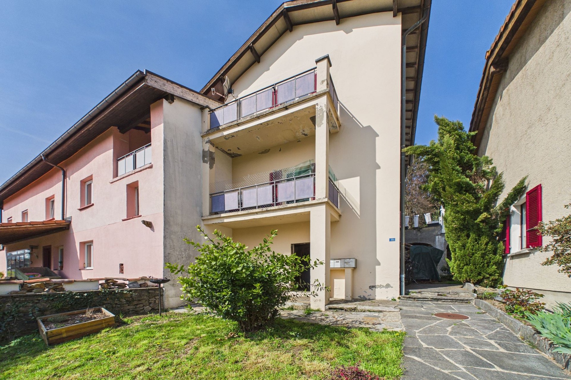Außenansicht eines Wohnhauses mit Balkon und Garten