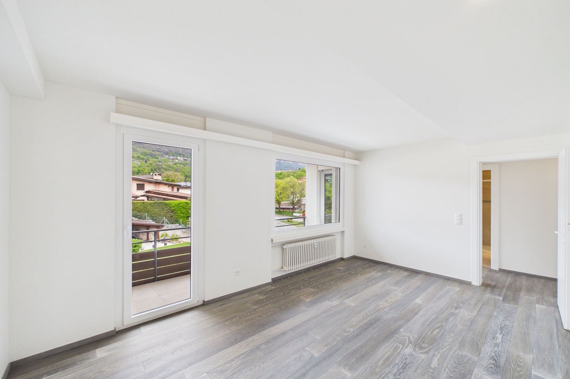 Heller leerer Wohnraum mit Balkon und Ausblick