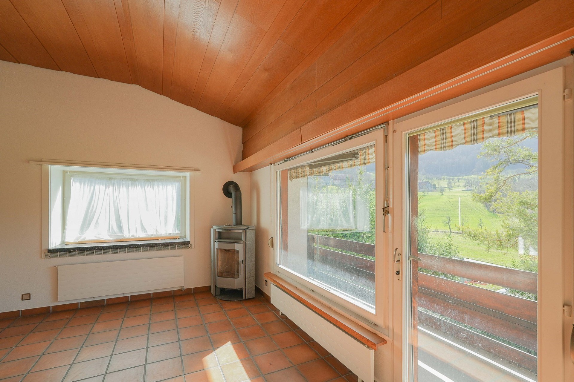 Heller Wohnraum mit Holzdecke und Blick ins Grüne