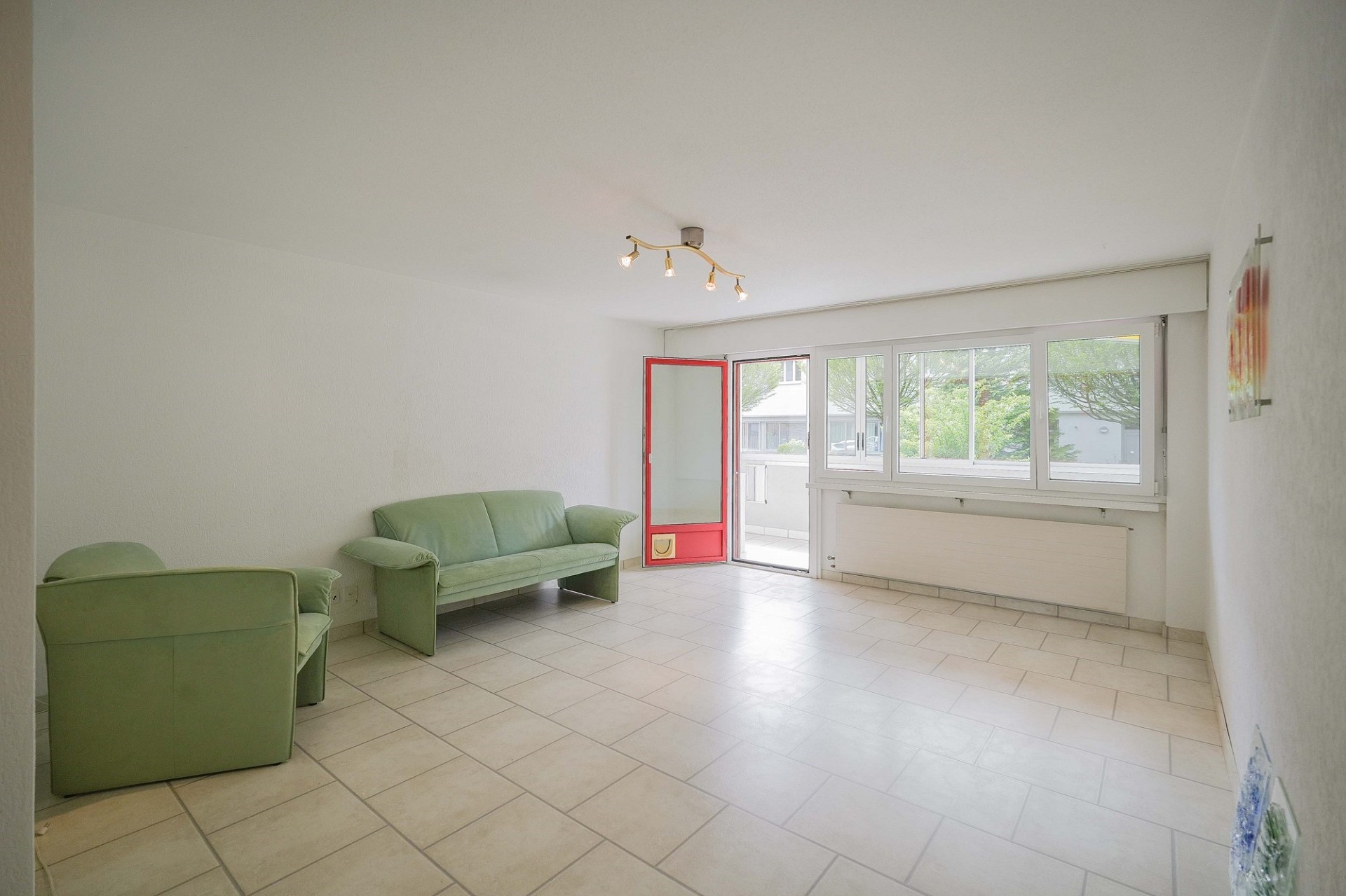 Heller Wohnraum mit grünem Sofa und Balkonzugang