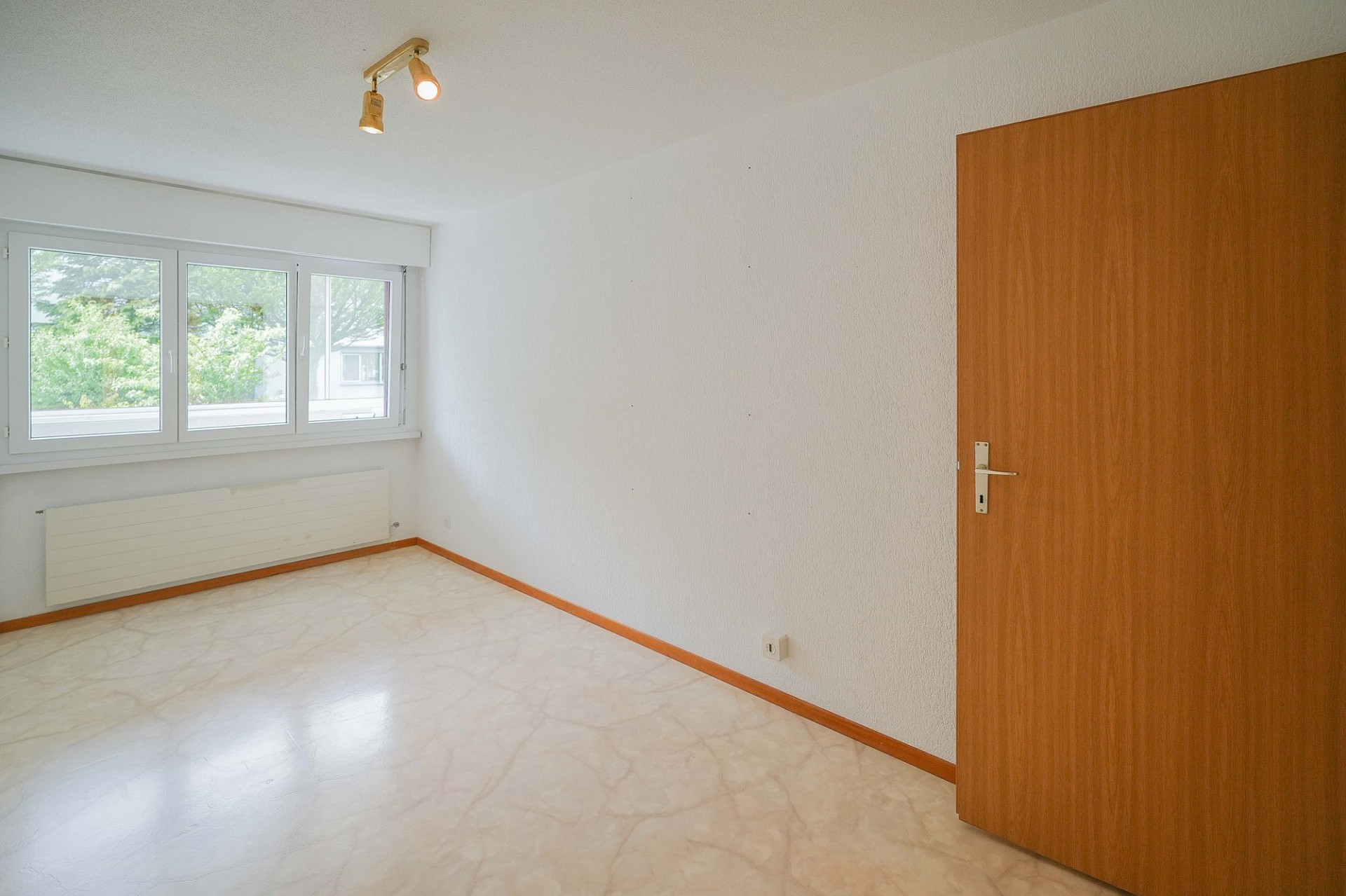 Leerer heller Raum mit Fenster und Holztür