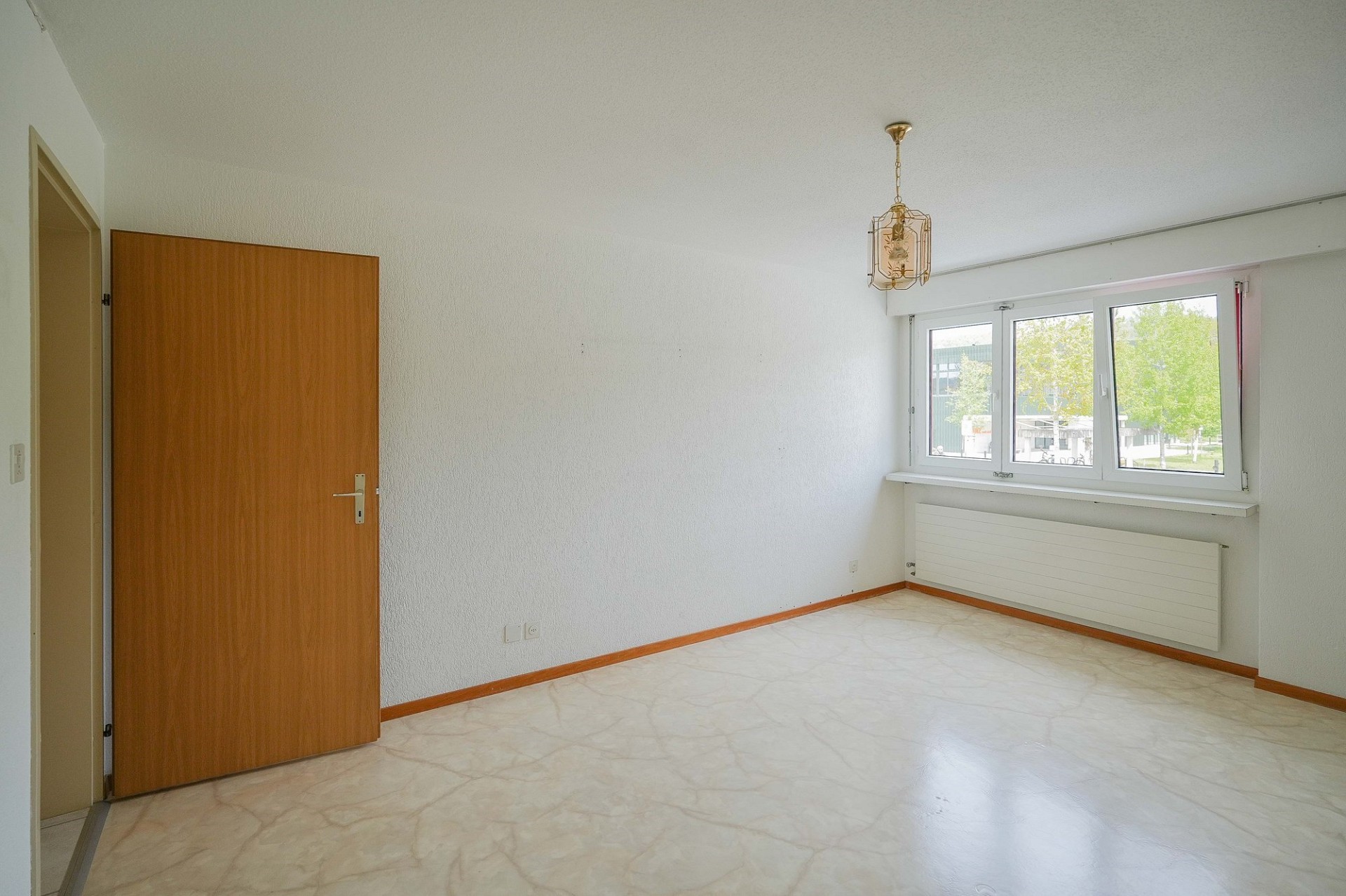 Helles, leeres Zimmer mit Fenster und Holztür