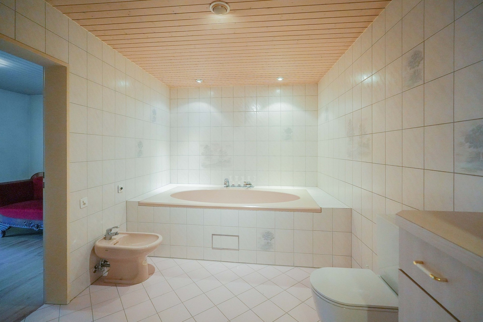 Großes, hell gefliestes Badezimmer mit Wanne und Bidet