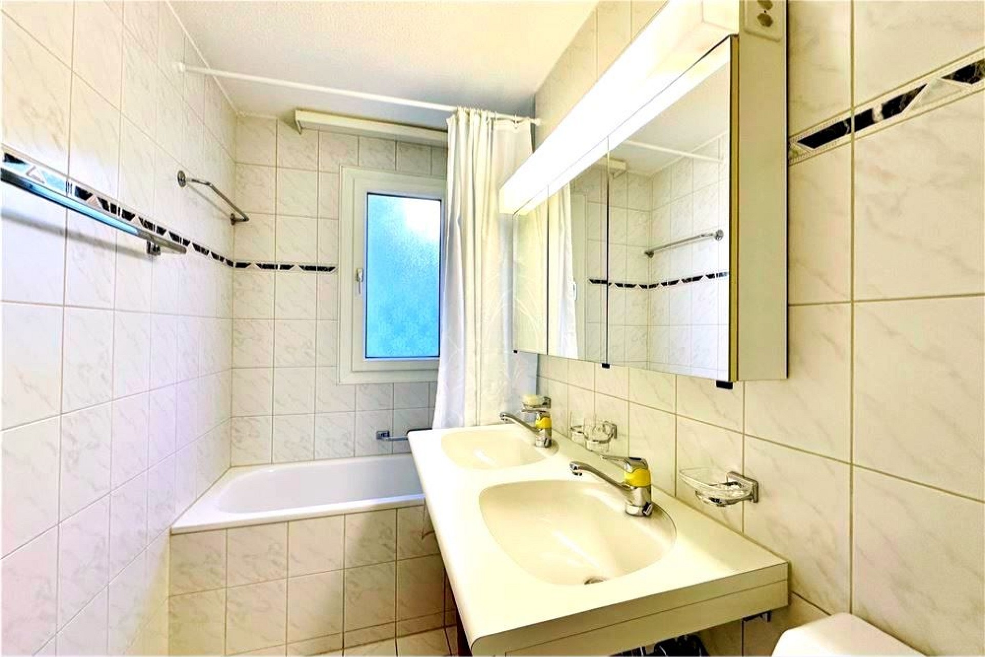 Helles Badezimmer mit Badewanne und Doppelwaschtisch
