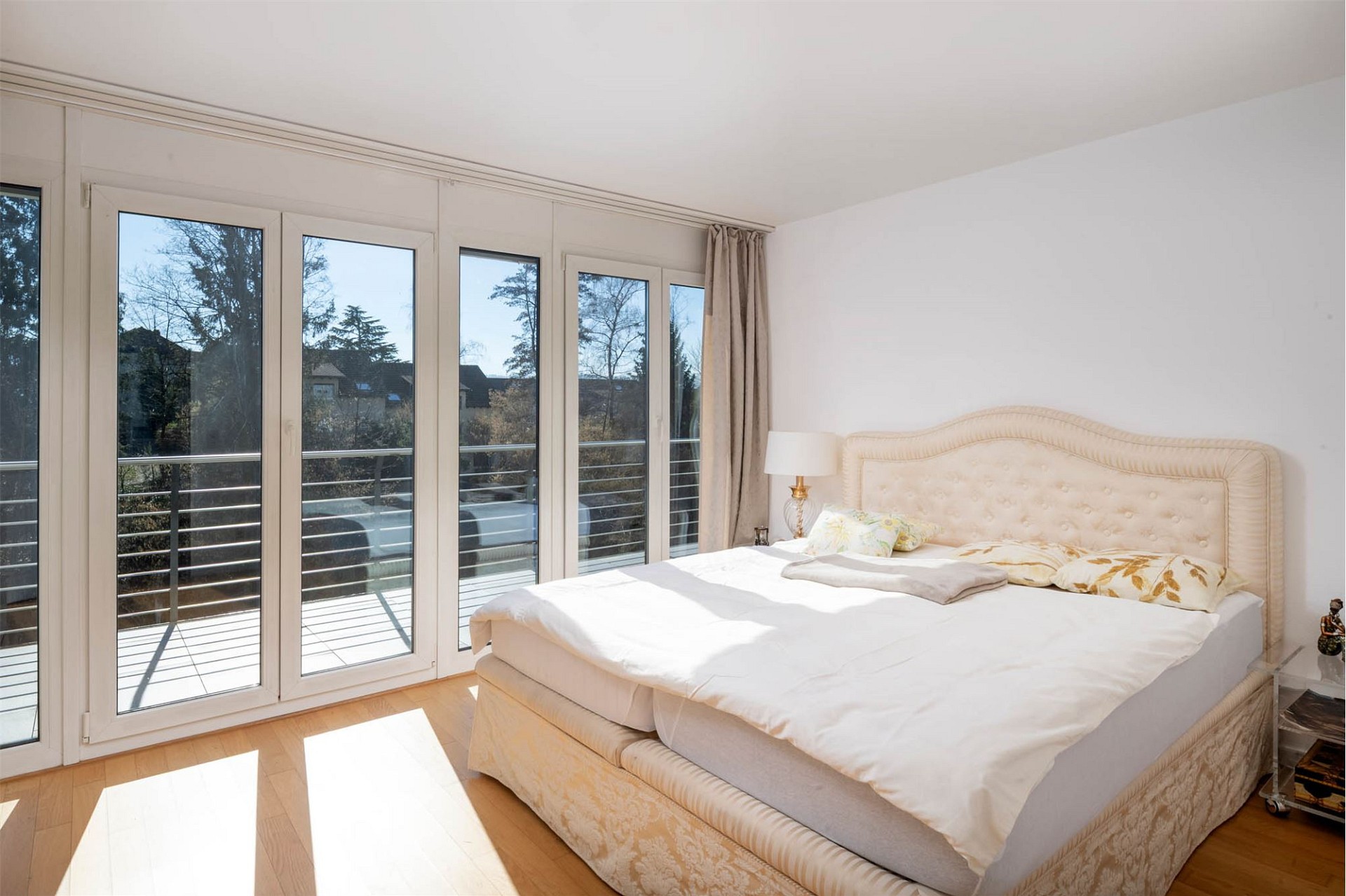 Helles Schlafzimmer mit großflächigen Fenstern und Balkonzugang