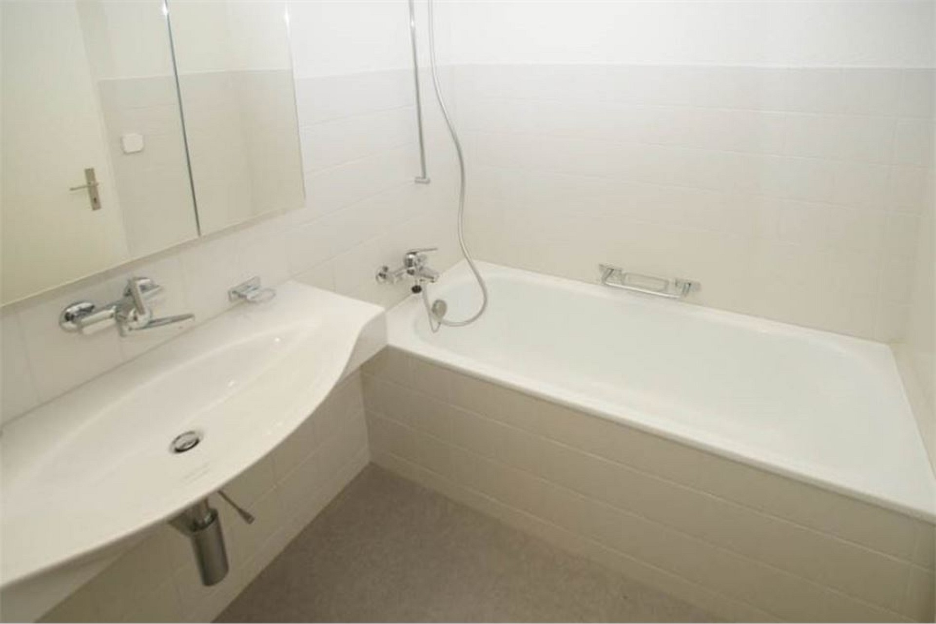 Hell gefliestes Badezimmer mit Doppelwaschbecken und Badewanne