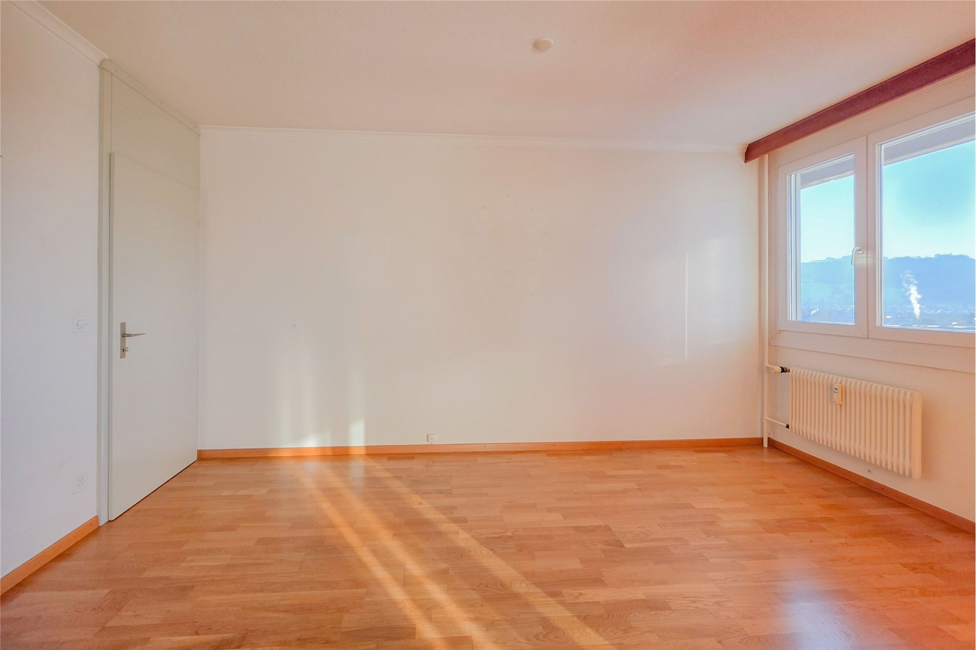Leeres, helles Zimmer mit Fenster und Heizkörper