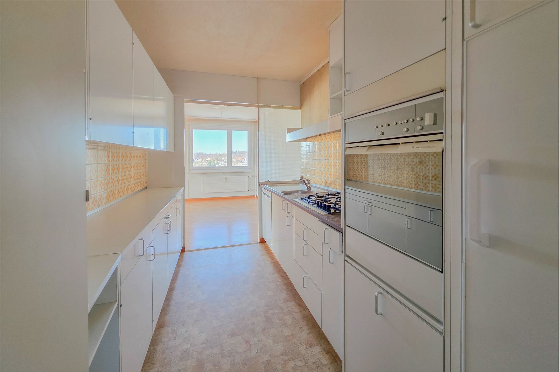 Schmale Einbauküche mit Durchblick ins Wohnzimmer