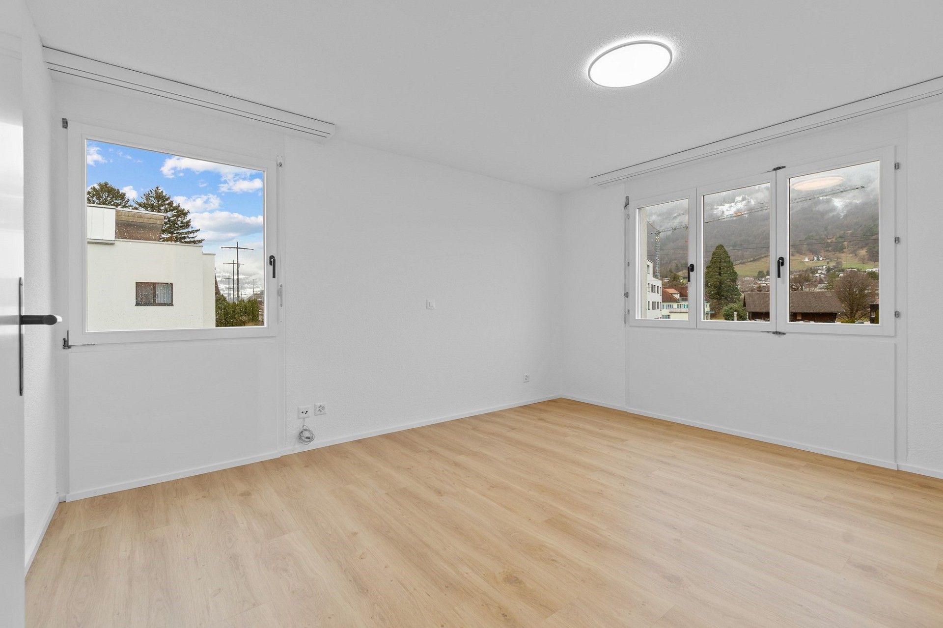 Heller leerer Wohnraum mit großen Fenstern und Ausblick