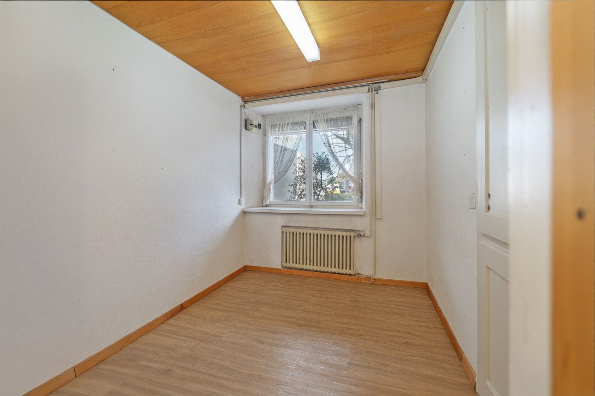 Kleines leeres Zimmer mit Fenster und Heizung