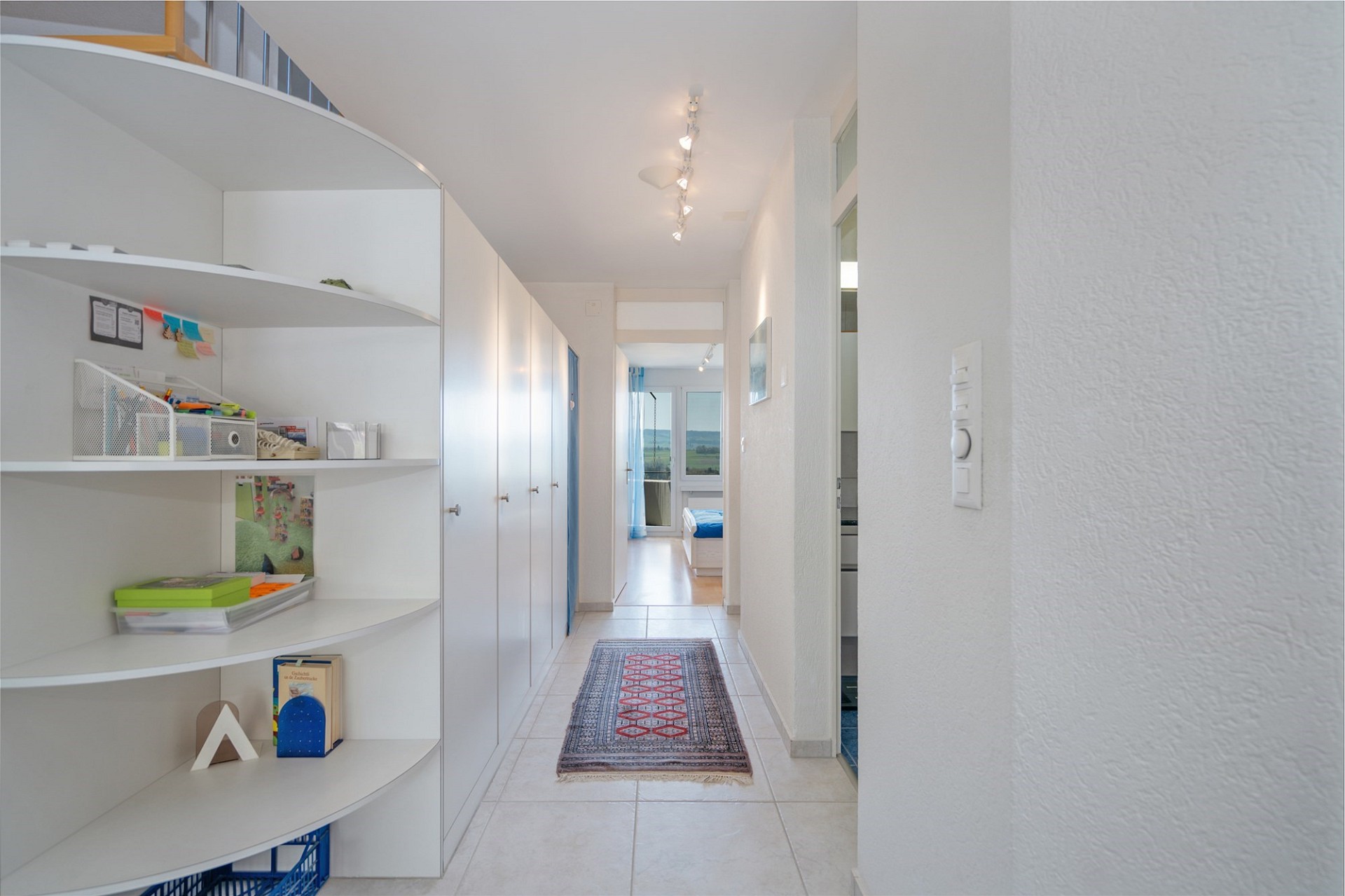 Heller Flur mit Regal und Blick ins Schlafzimmer