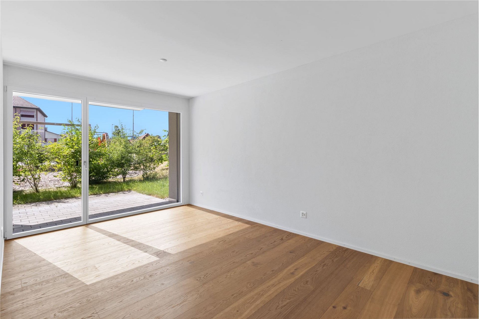 Leerer Wohnraum mit Terrasse und Gartenblick