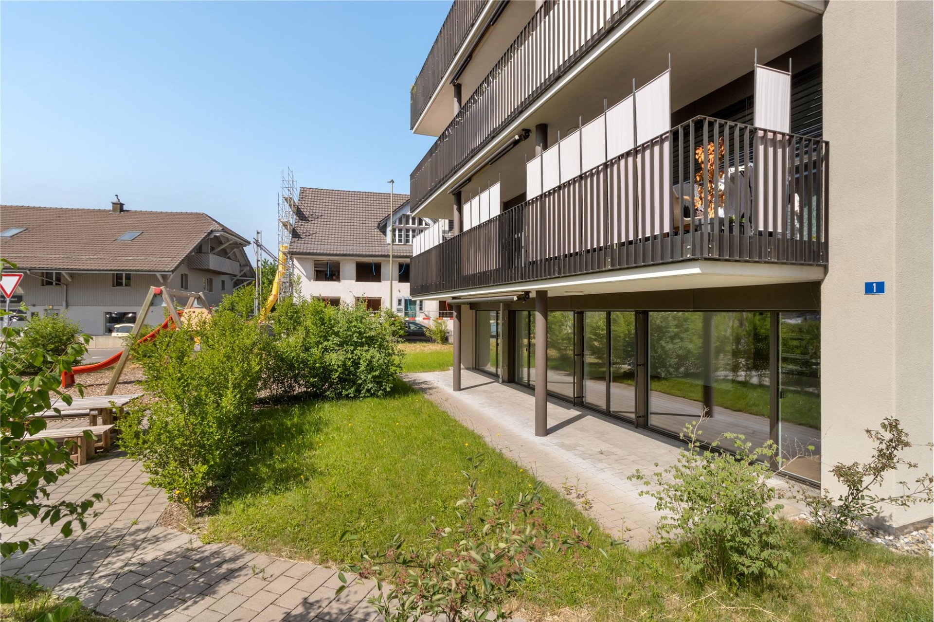 Außenansicht eines modernen Mehrfamilienhauses mit Balkon und Garten