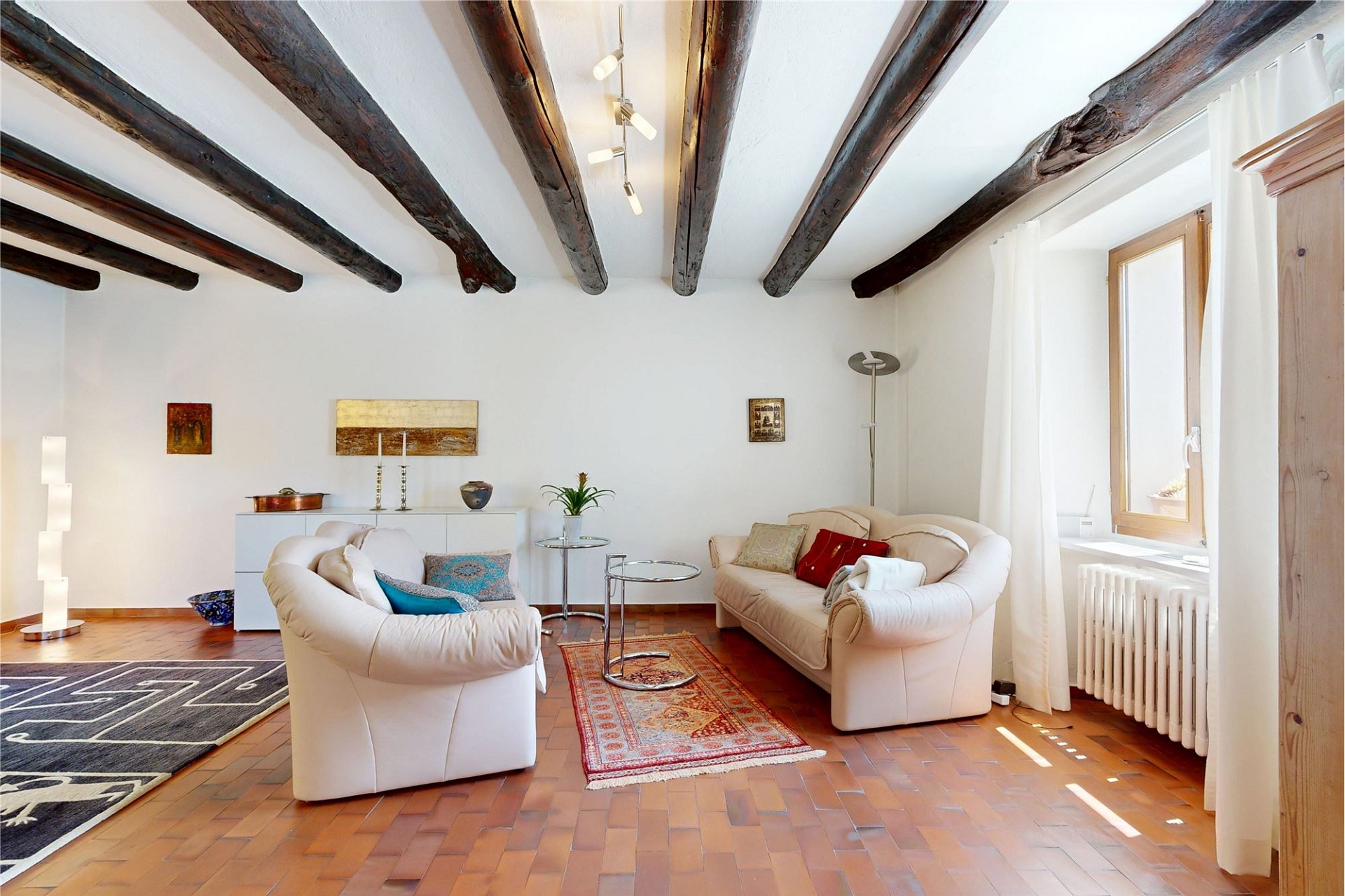 Wohnzimmer mit sichtbaren Holzbalken und hellem Interieur