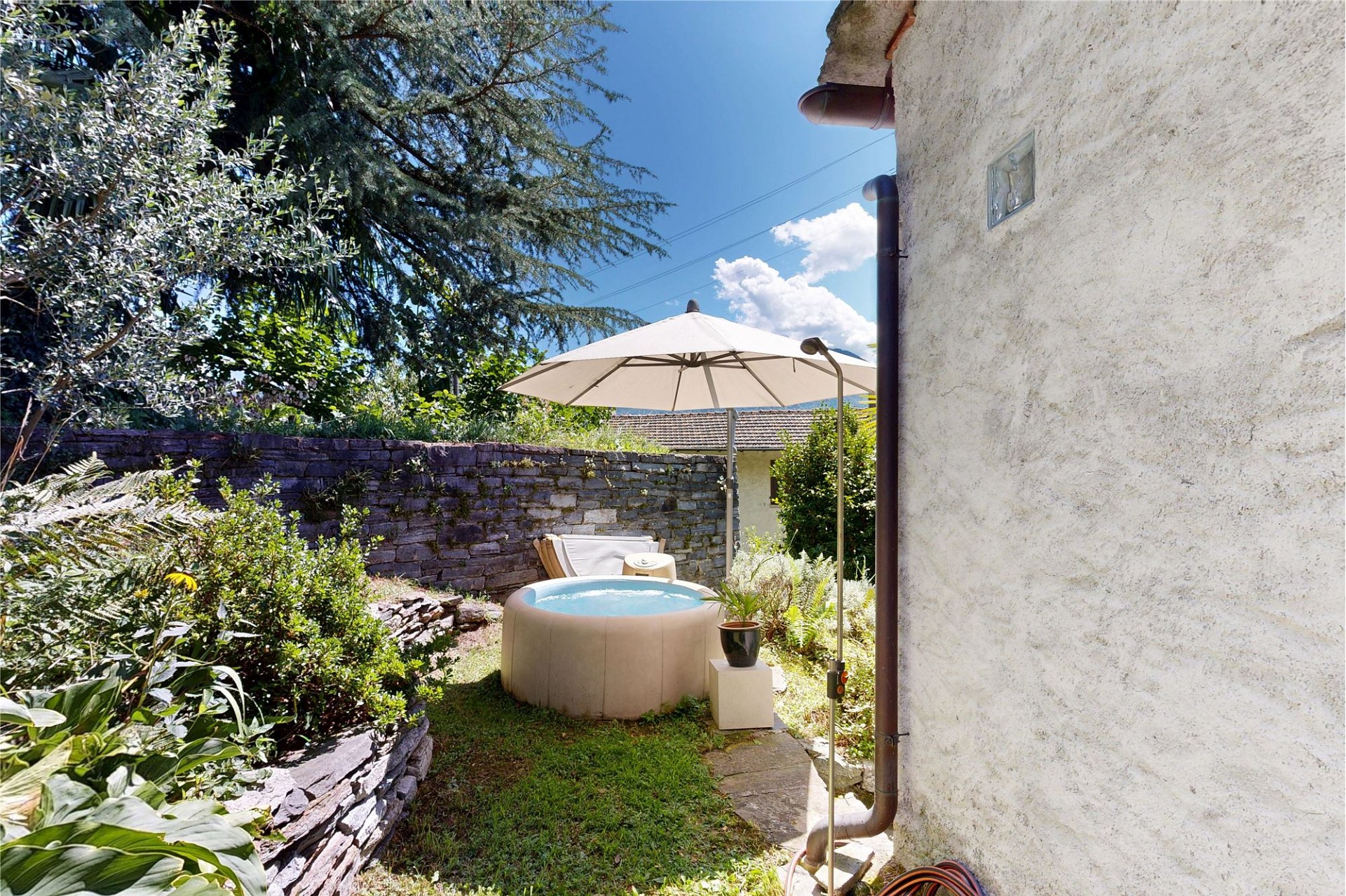 Garten mit Whirlpool und Sonnenschirm