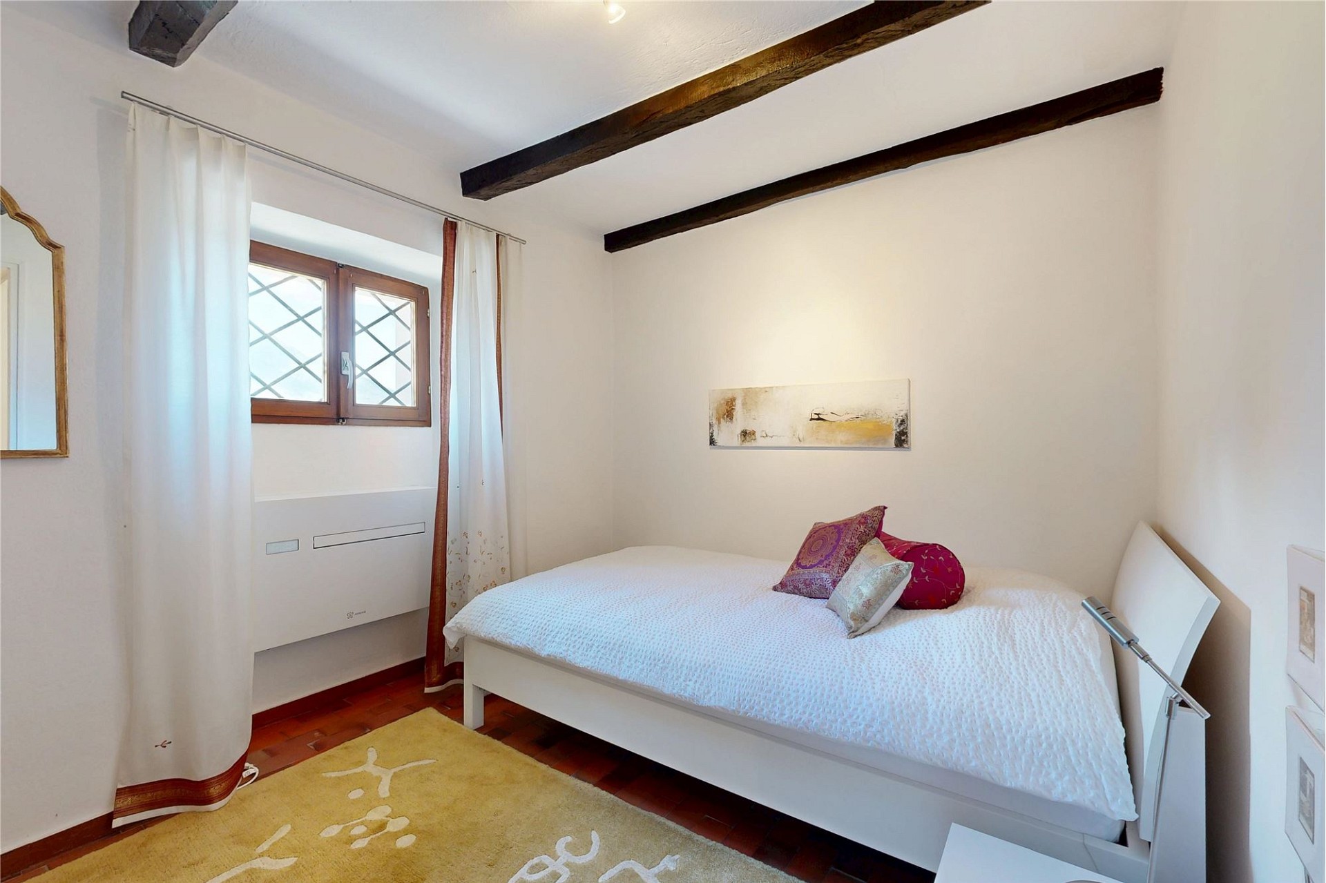Helles Schlafzimmer mit Holzbalken und Einzelbett