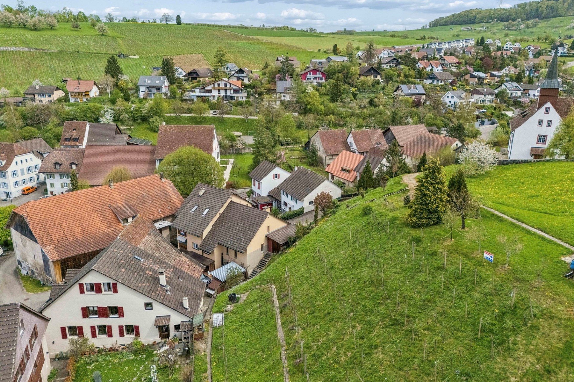 Luftaufnahme eines ländlichen Dorfes mit Häusern und grünen Hängen