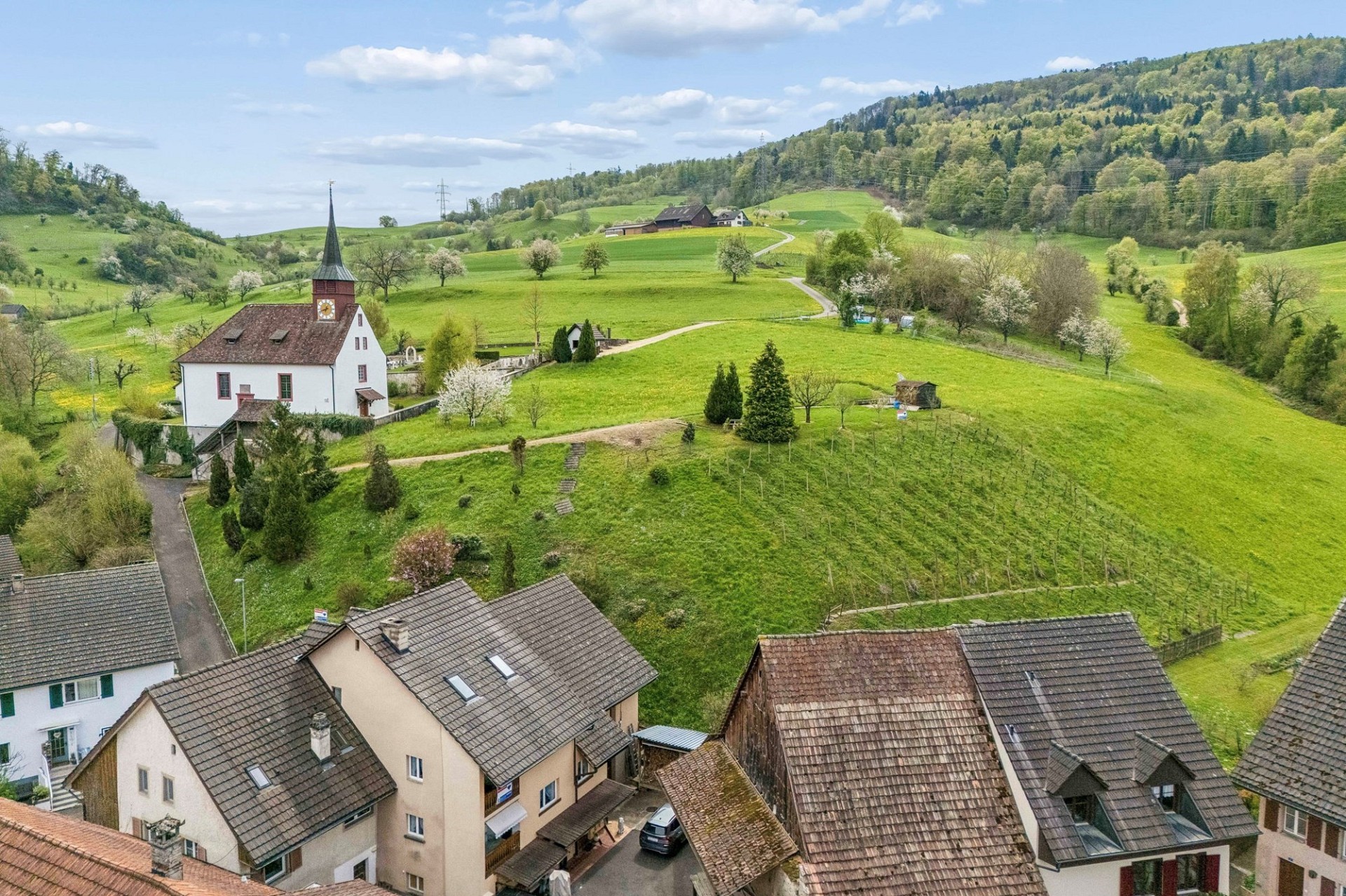 Luftaufnahme eines ländlichen Tals mit Kirche und Höfen