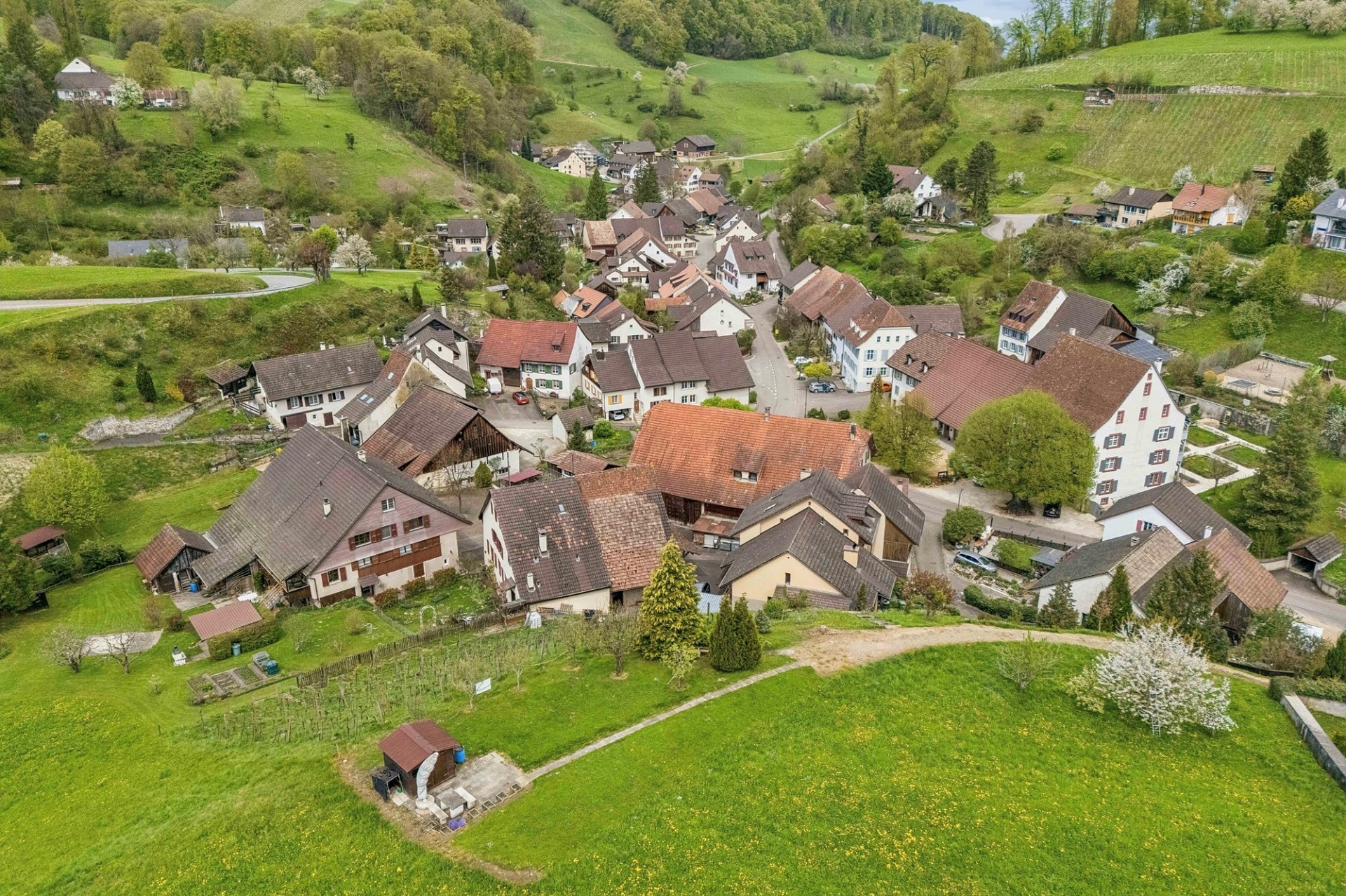 Luftaufnahme eines ländlichen Dorfes in grüner Hügellandschaft